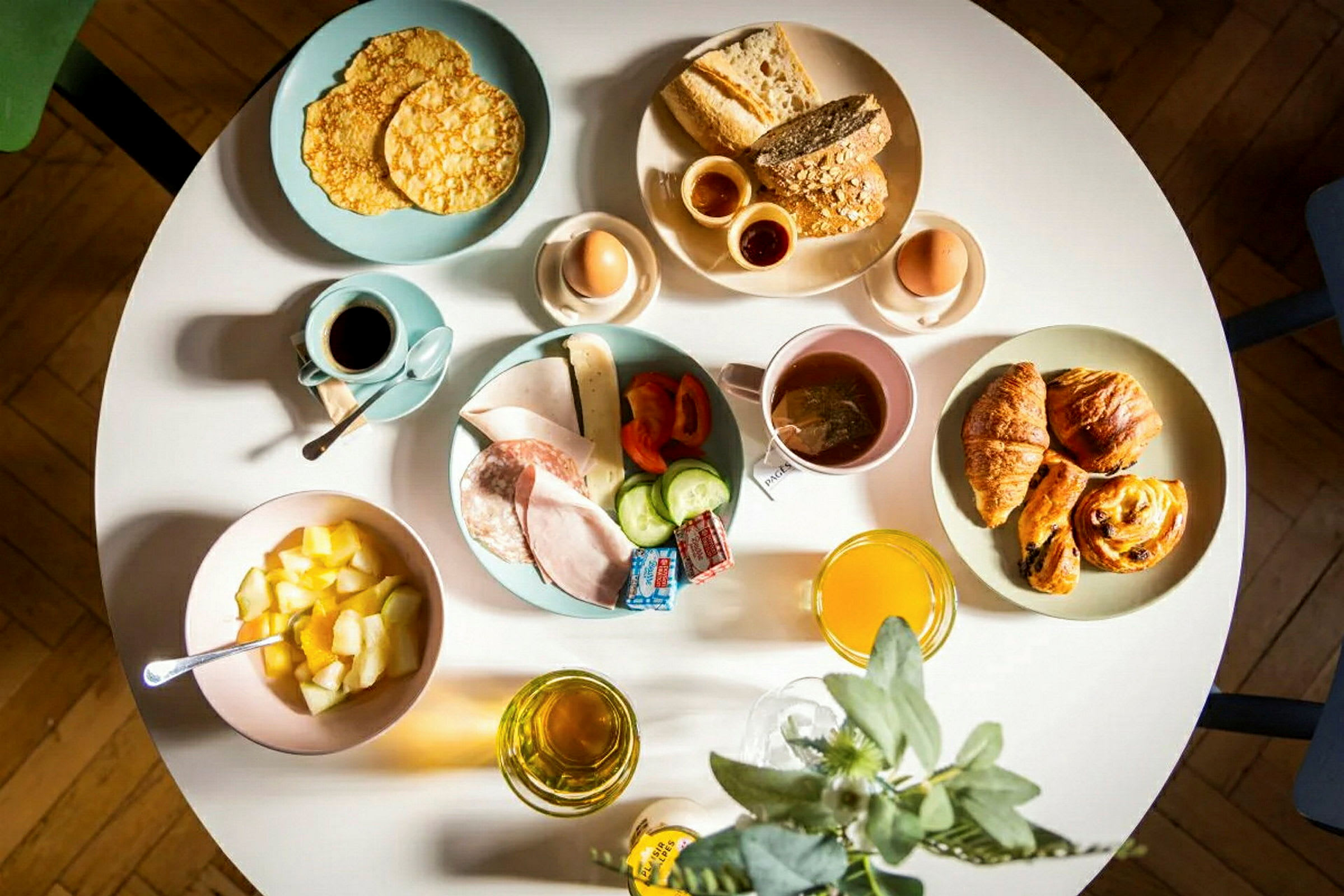 En frukostservering med bröd, bakverk, ägg, frukt, pålägg och drycker. (AI-genererad text)