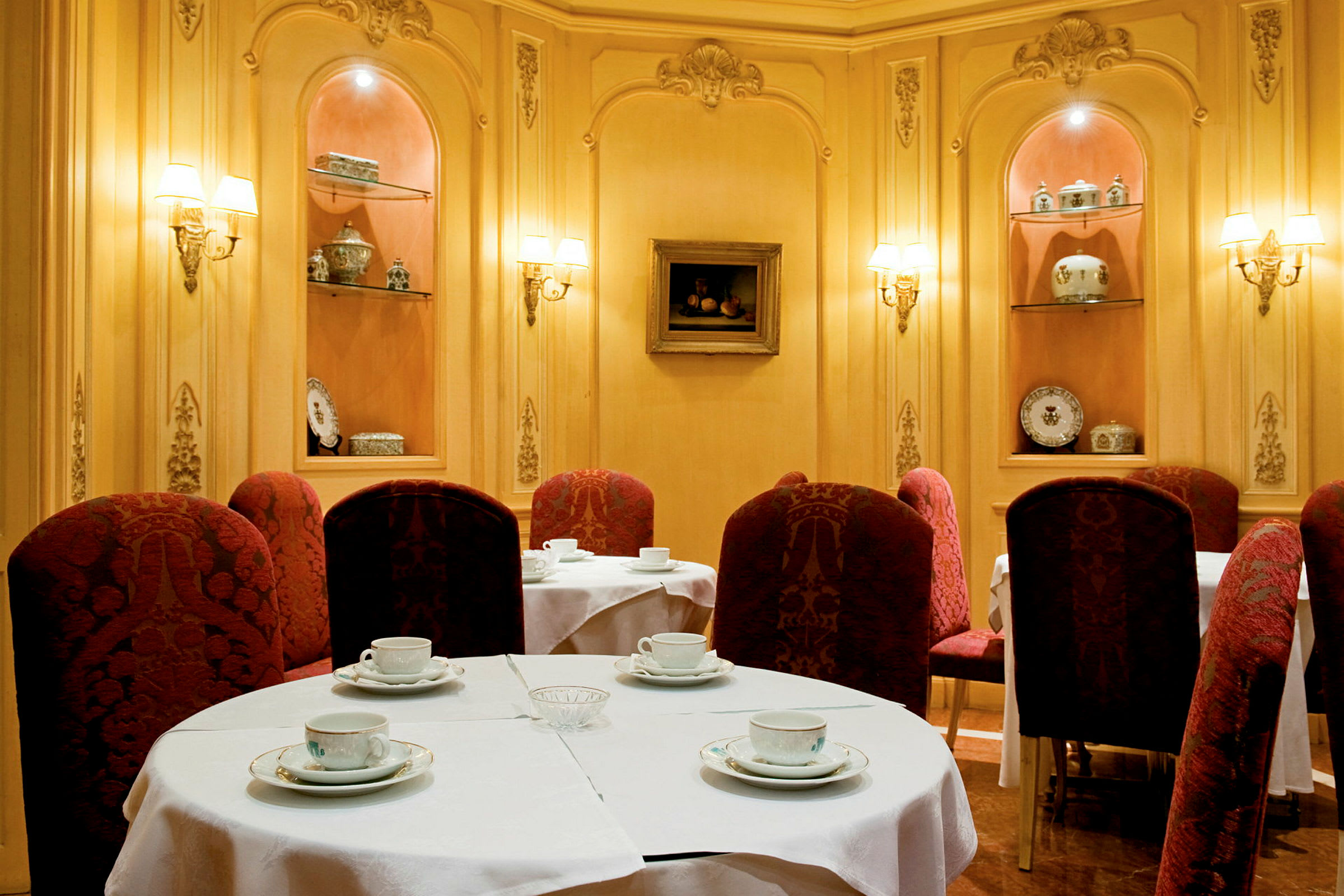 Ett elegant inrett kafé med bord täckta av vita dukar och röda stolar. (AI-genererad text)