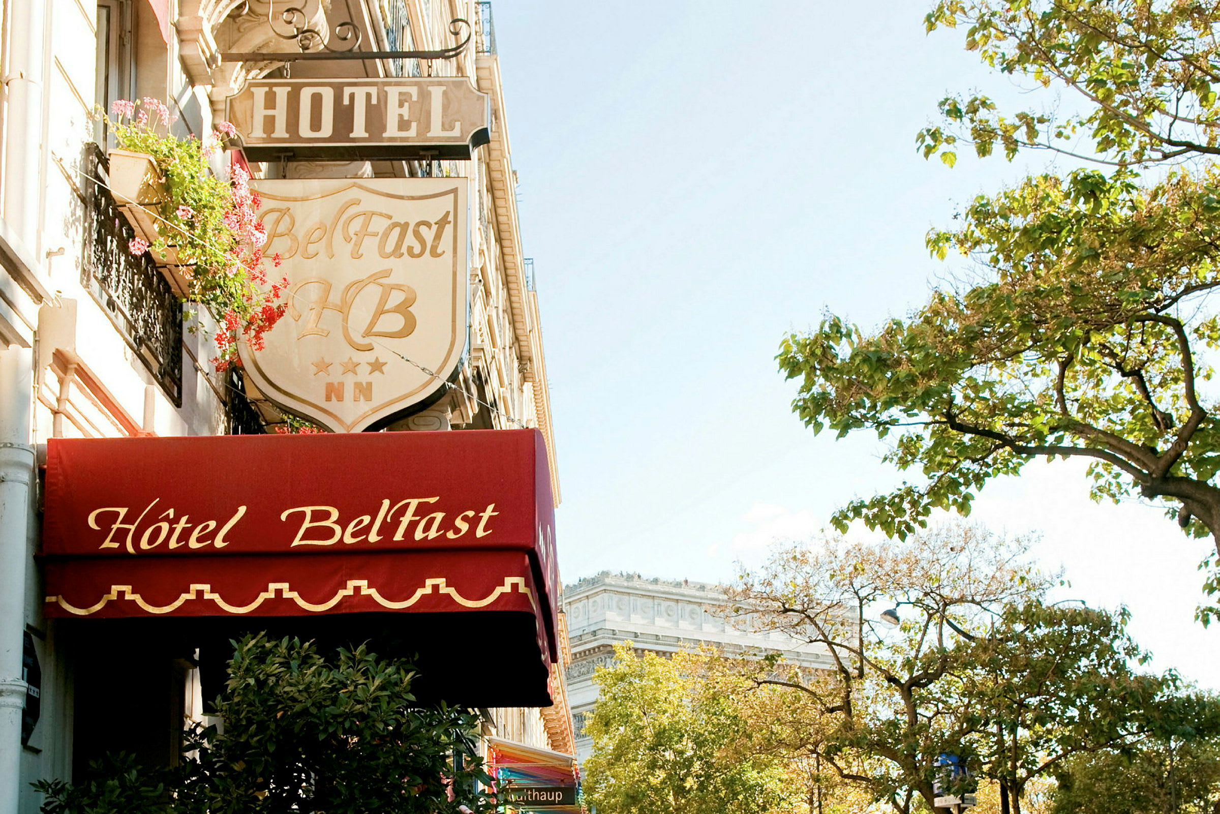 Fasad av Hotel Belfast med skyltar och träd i närheten. (AI-genererad text)