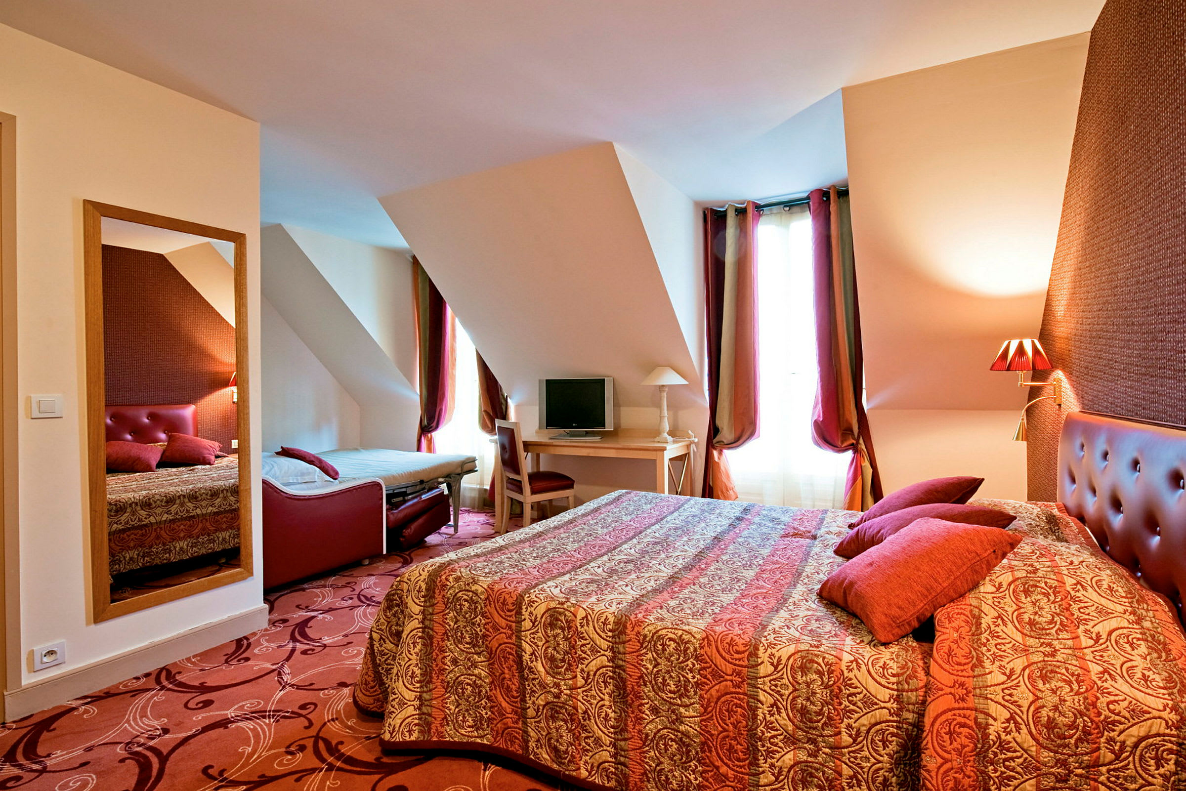 Ett hotellrum med dubbelsäng, extra säng och skrivbord. (AI-genererad text)