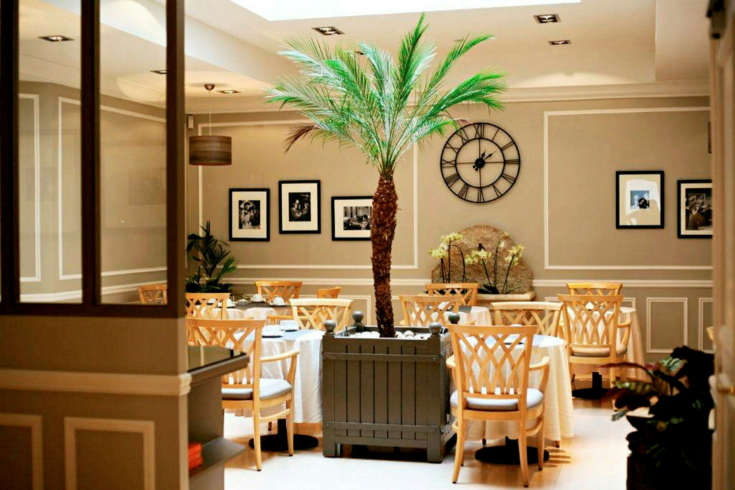 Inne i ett elegant café med ett centralt placerat palmerträd och dekorativa inslag. (AI-genererad text)