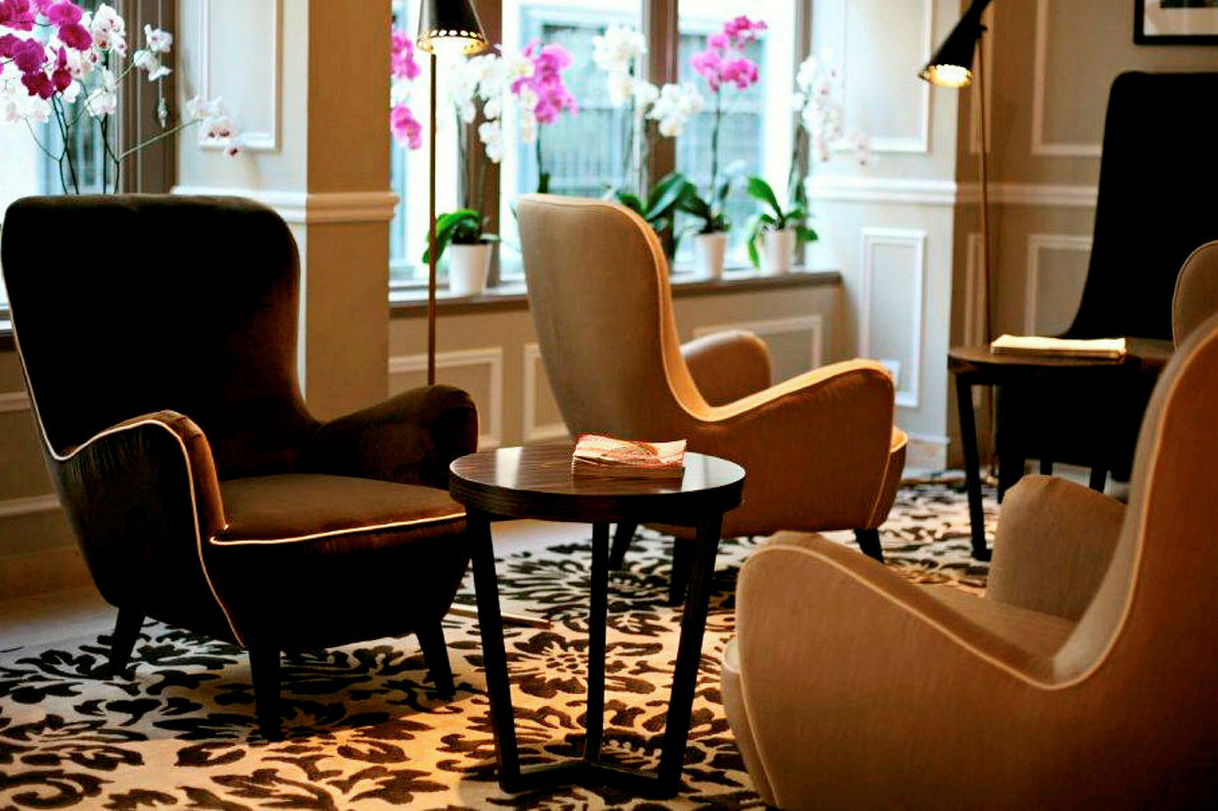 En lounge med bekväma fåtöljer, ett bord och dekorativa blommor i fönstren. (AI-genererad text)