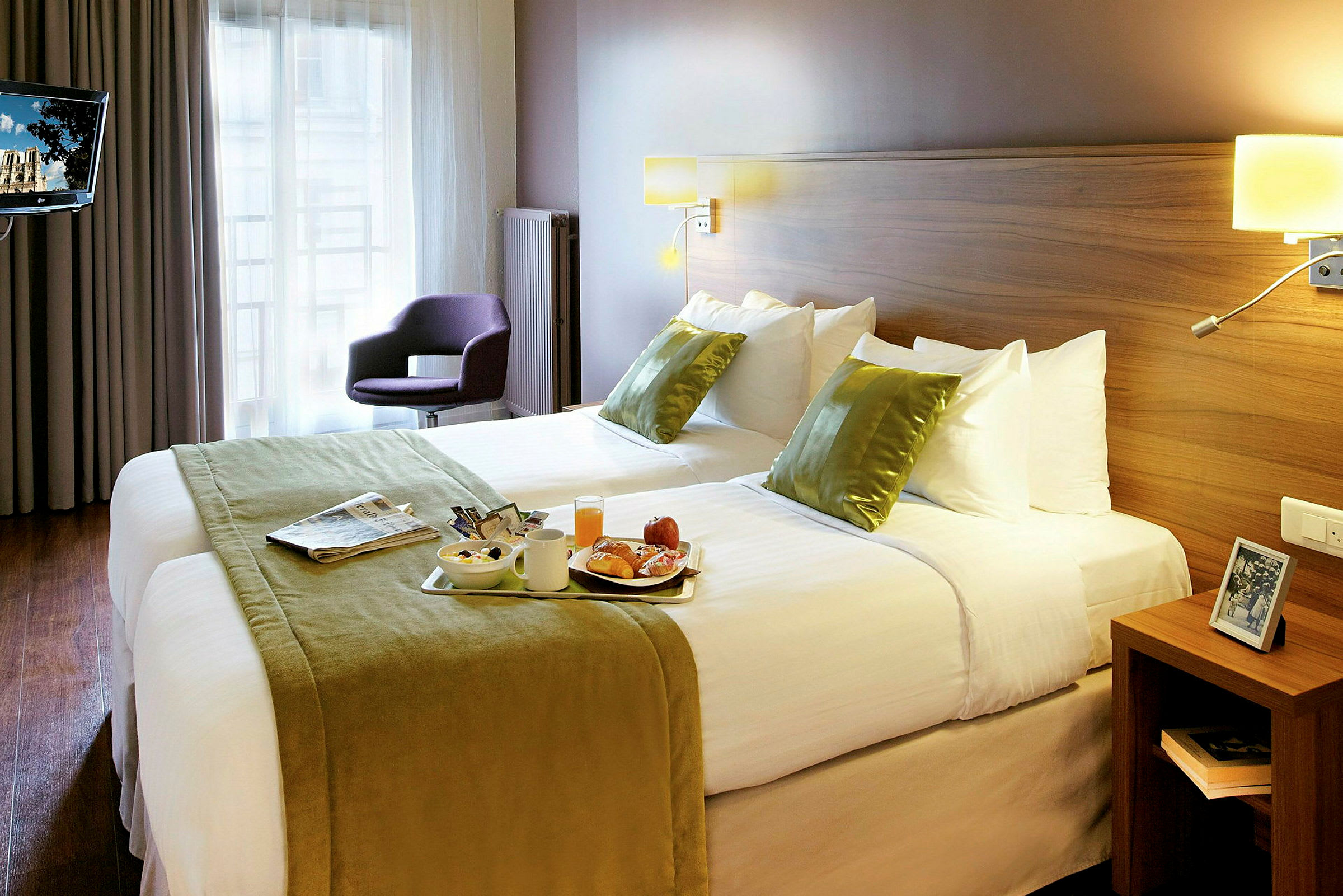 Ett hotellrum med en stor säng, ljus inredning och ett frukostbricka på sängen. (AI-genererad text)