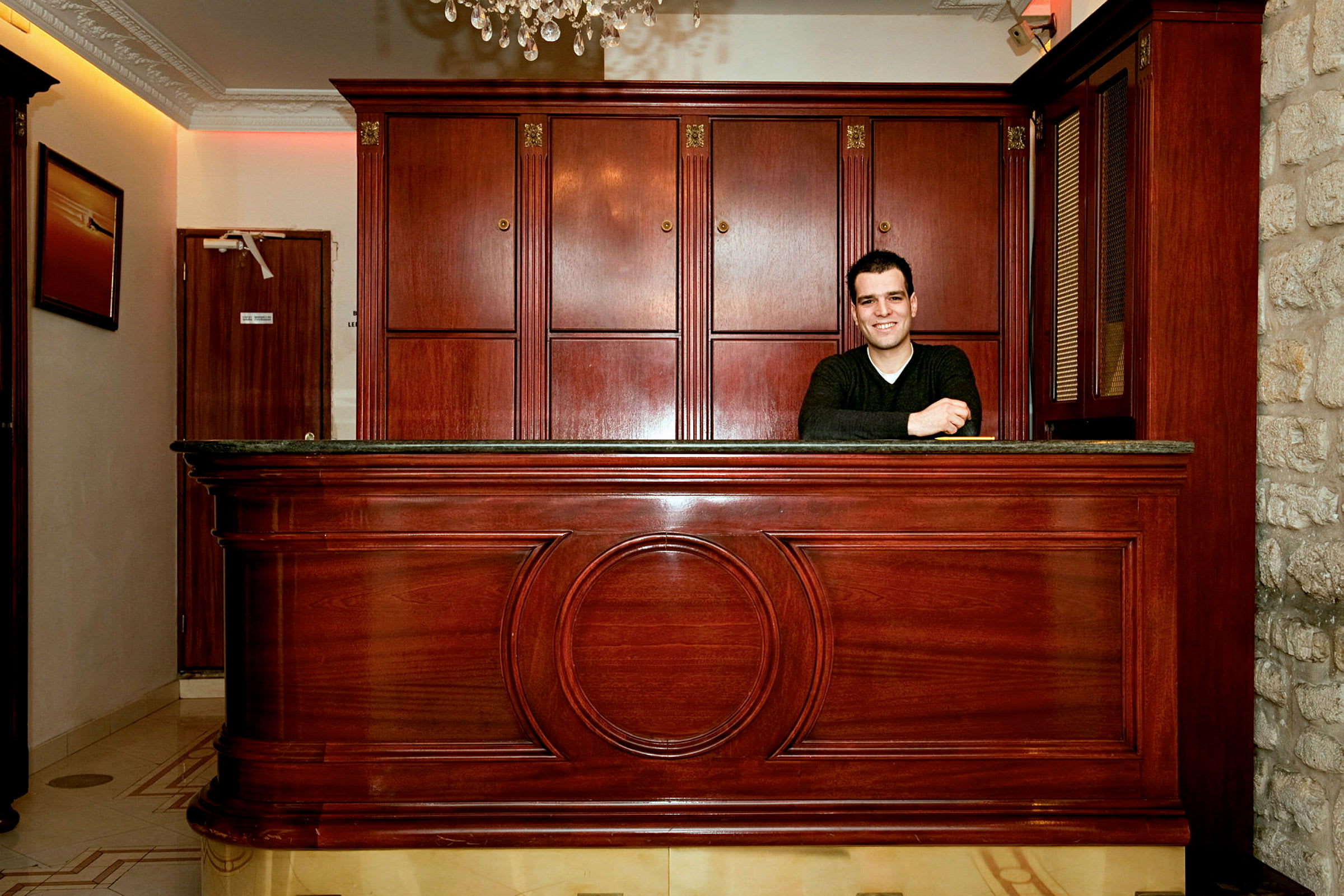 En receptionsdisk i ett hotell med träpaneler och dekorativ design. (AI-genererad text)