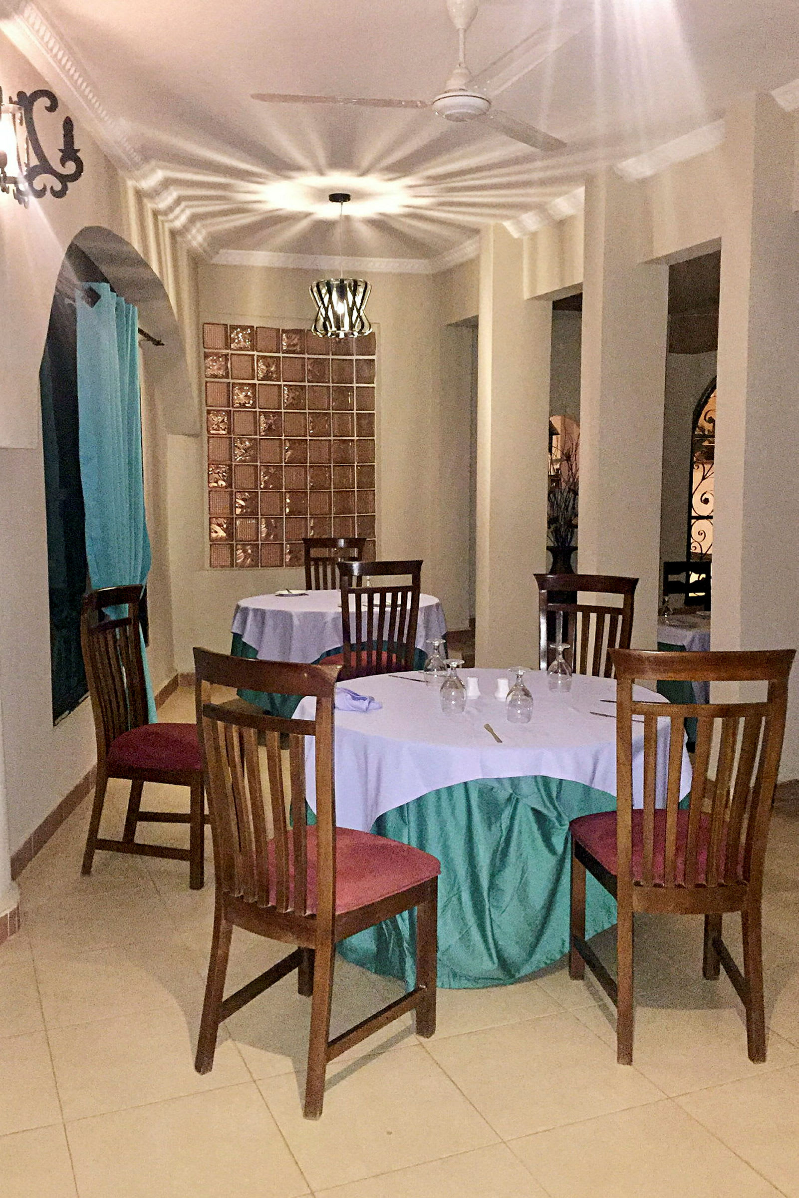 En restaurang med bord klädda i vita och gröna dukar, omgivna av trästolar. (AI-genererad text)