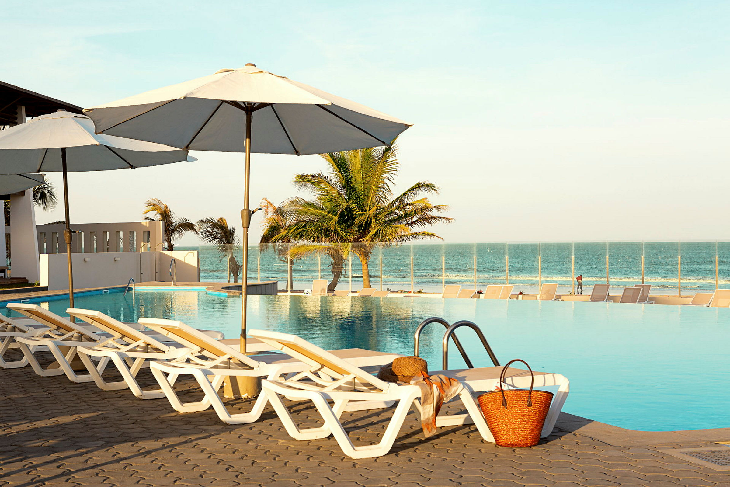 Solstolar vid en pool med paraplyer och utsikt över havet. (AI-genererad text)