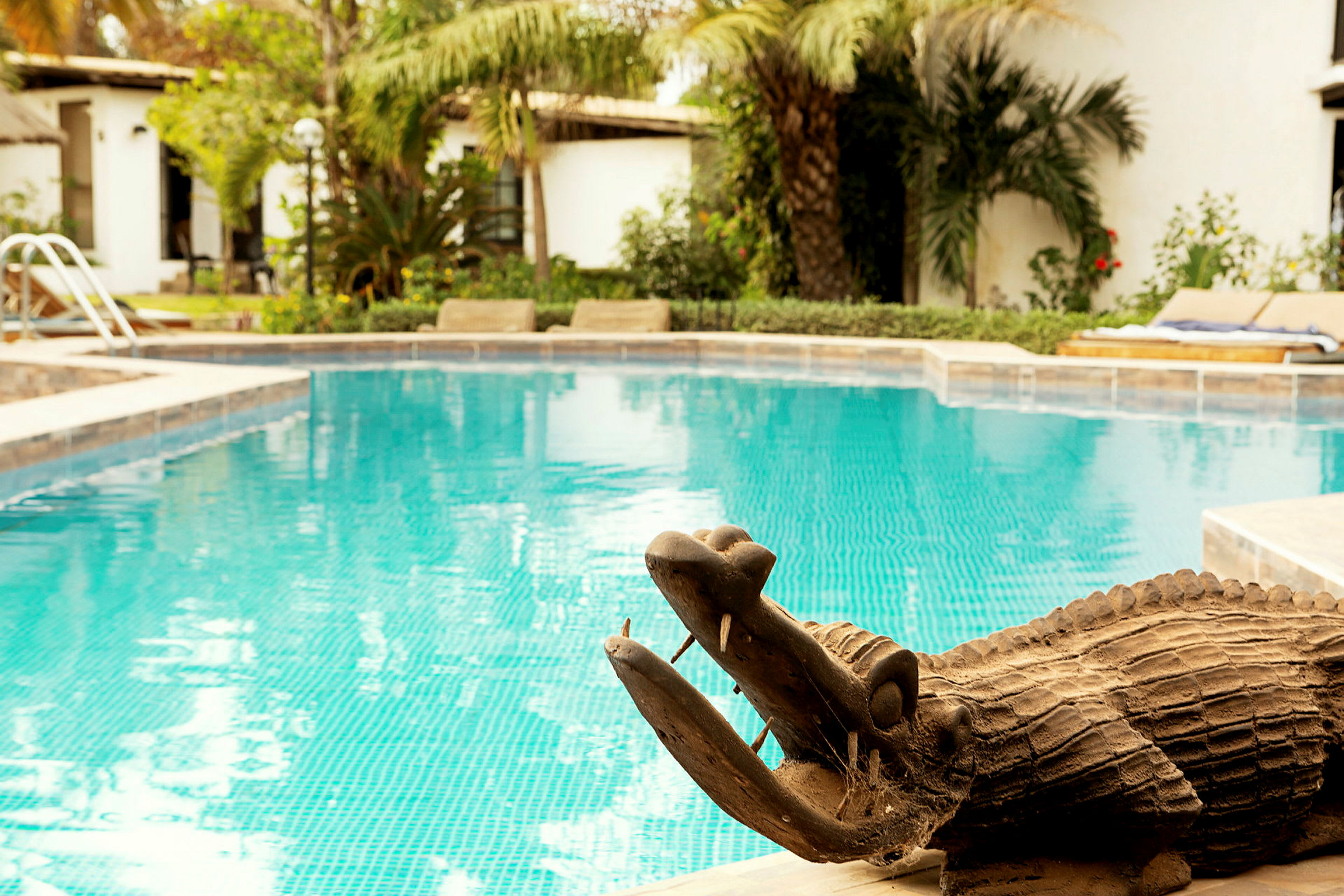 En träskulptur föreställande en krokodil vid kanten av en pool. (AI-genererad text)
