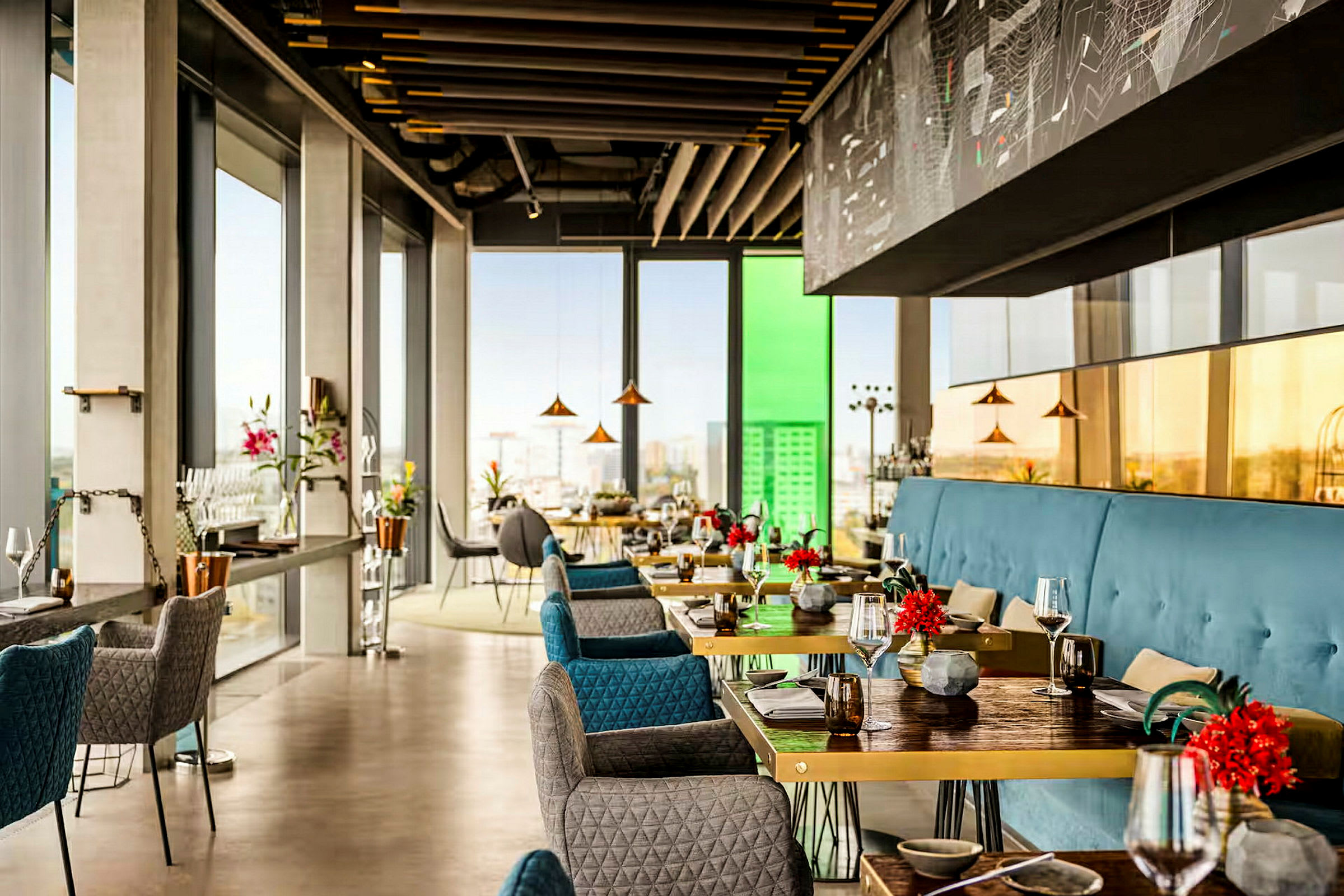 En elegant, modern restaurang med stora fönster som släpper in mycket ljus och utsikt över staden. Bordet är dekorerade med blommor. (AI-genererad text)