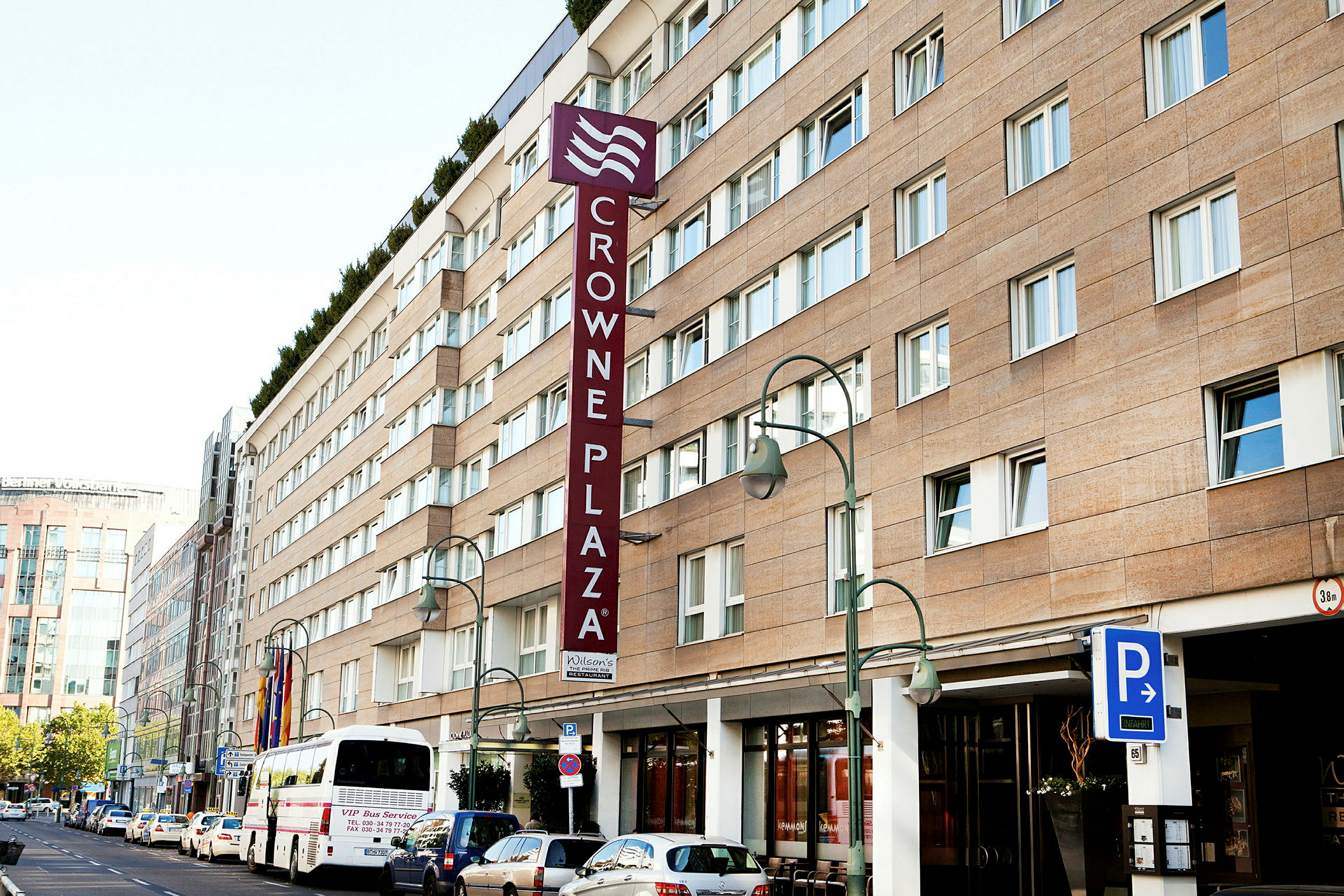 Crowne Plaza-hotellbyggnad med parkeringsskylt och buss framför. (AI-genererad text)