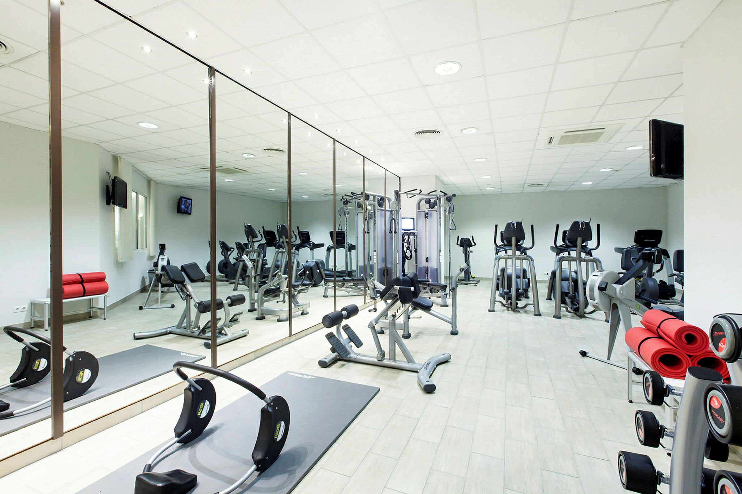 Ett gym med träningsutrustning och spegelväggar. (AI-genererad text)