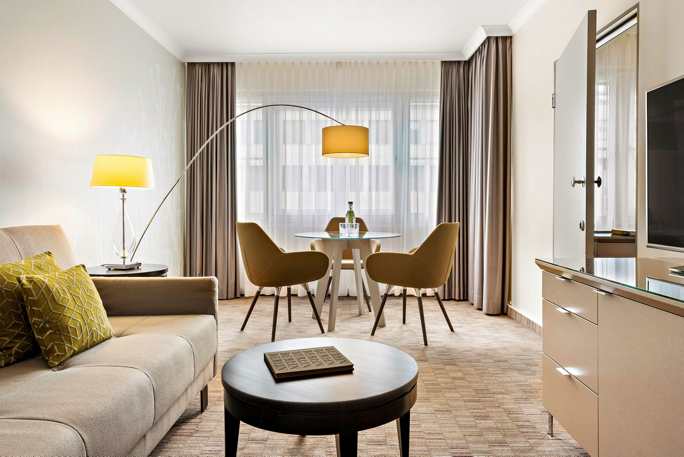 Ett modernt hotellrum med sittgrupp, bord med två stolar, soffa och lampor. (AI-genererad text)