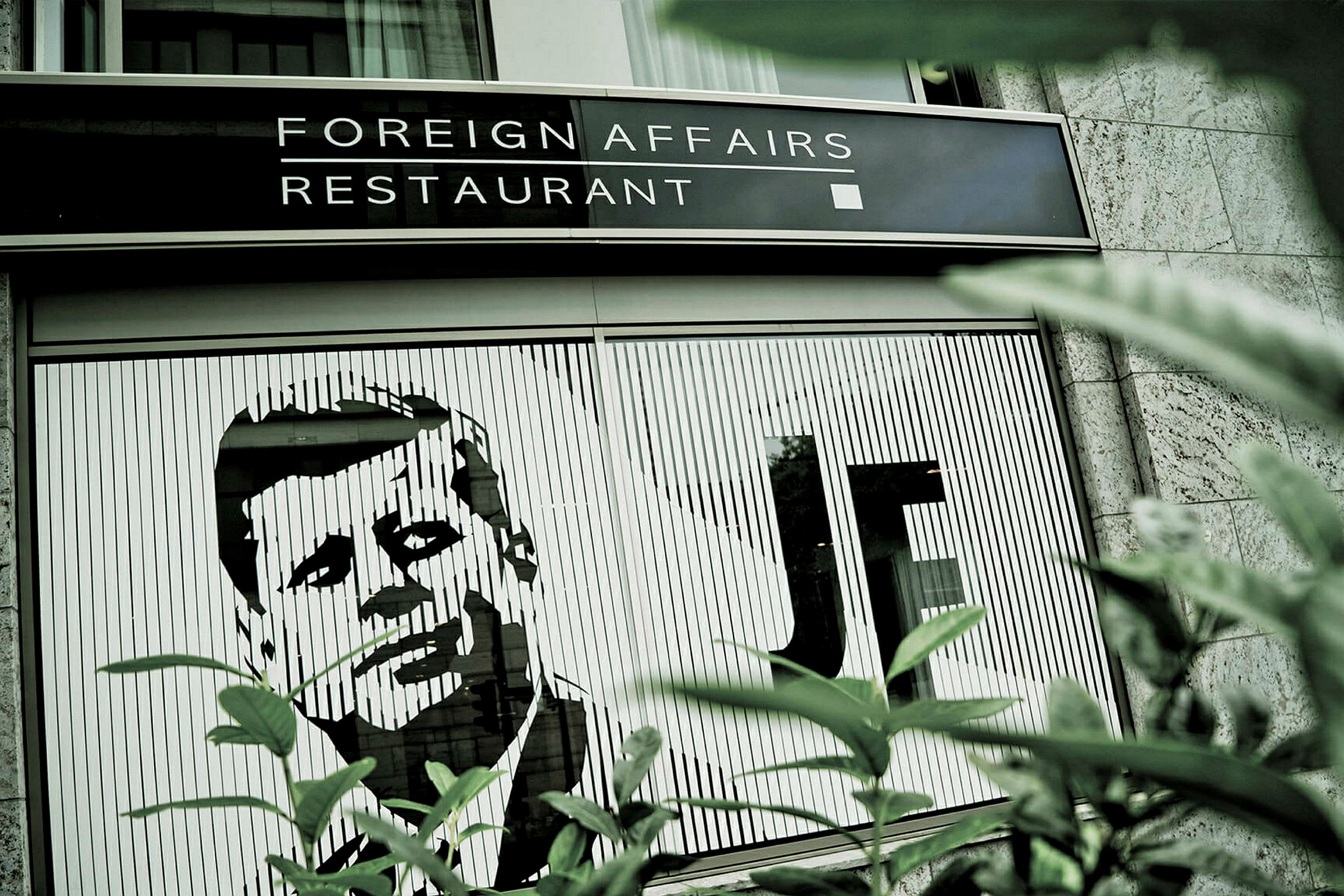 Bild på en restaurang med namnet 'Foreign Affairs Restaurant' samt en illustration av en man på byggnadens fasad. (AI-genererad text)