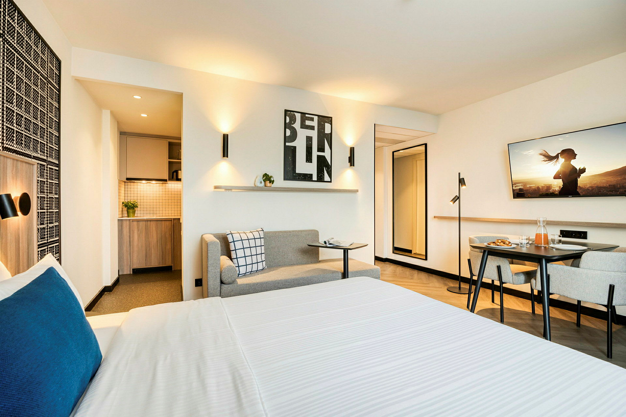 Interiör av ett modernt hotellrum med säng, liten köksdel och sittgrupp. (AI-genererad text)