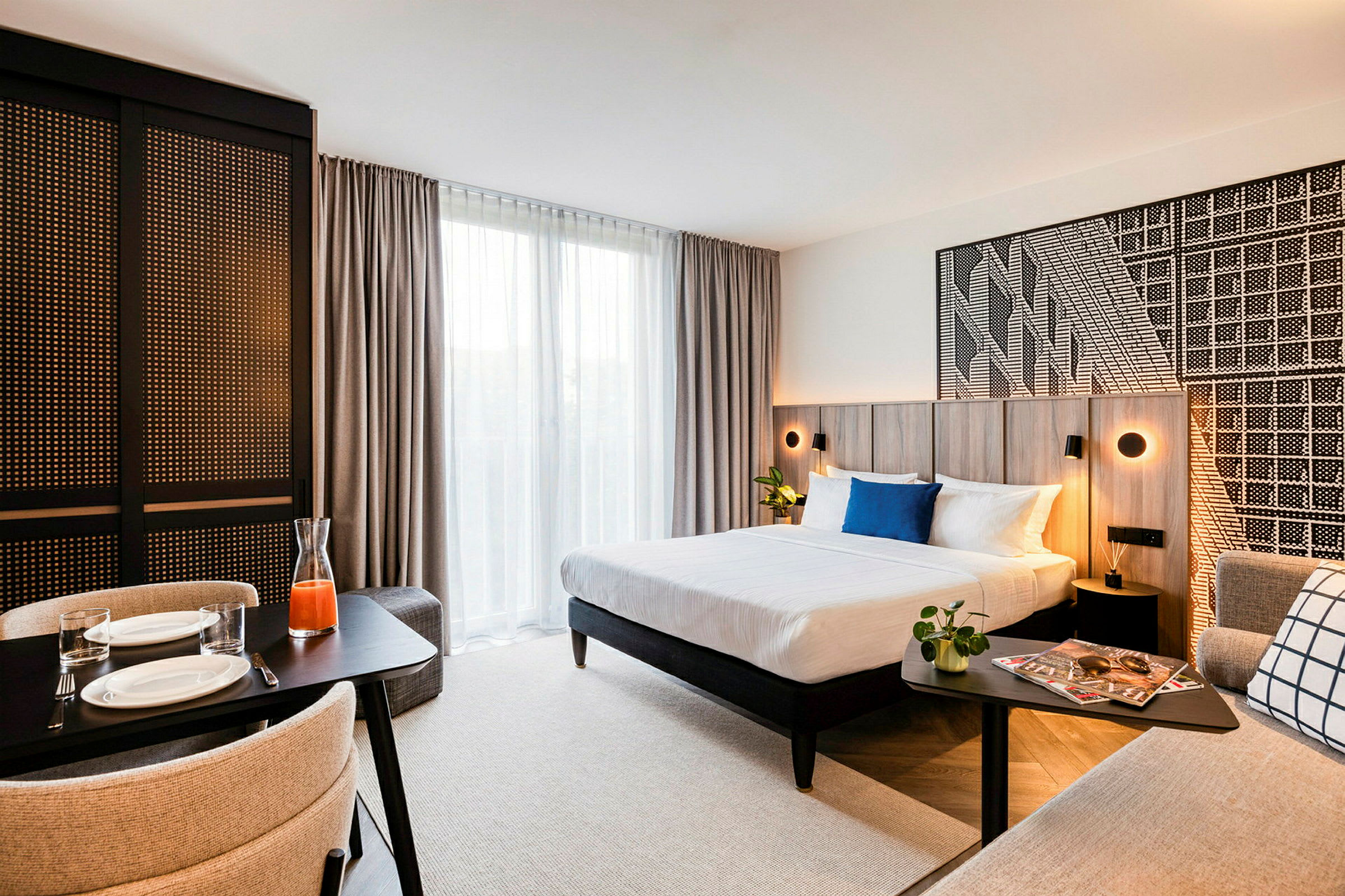 Ett modernt hotellrum med dubbelsäng, småbord och matplats. (AI-genererad text)