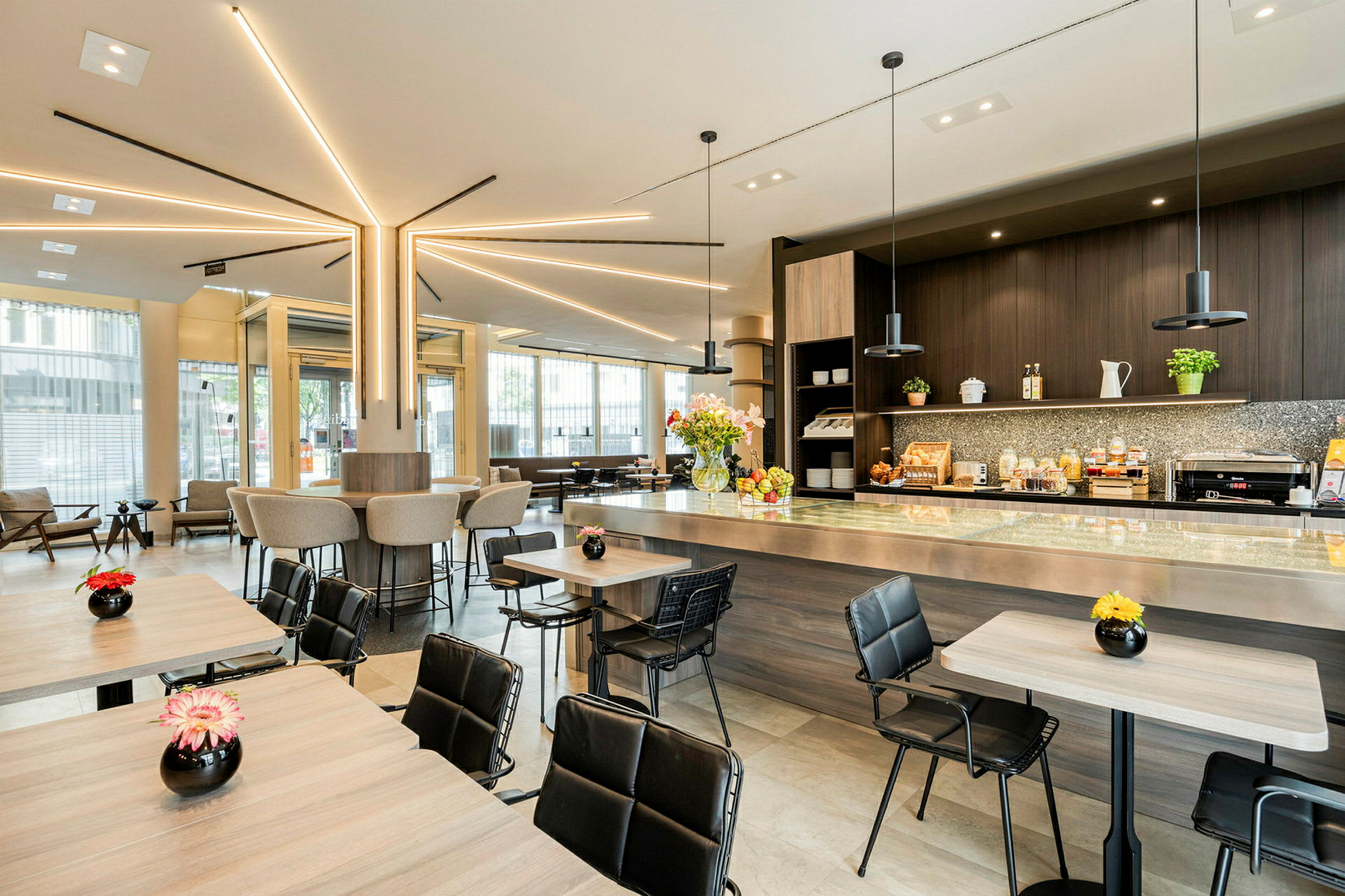 Modern cafémiljö med sittplatser vid bord och bardisk, dekorerad med blommor. (AI-genererad text)