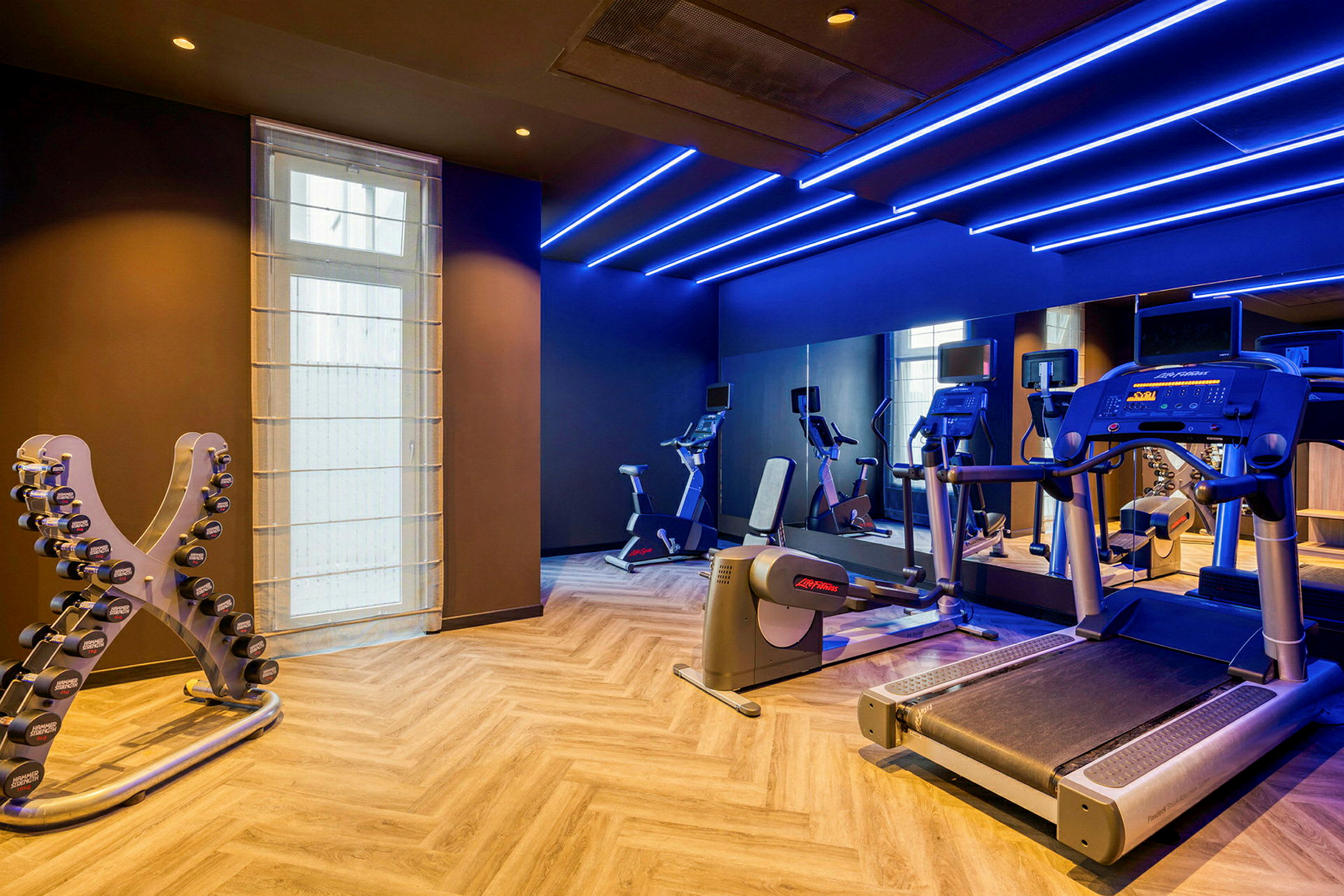Ett gym med träningsutrustning inklusive löpband, träningscyklar och hantlar. (AI-genererad text)