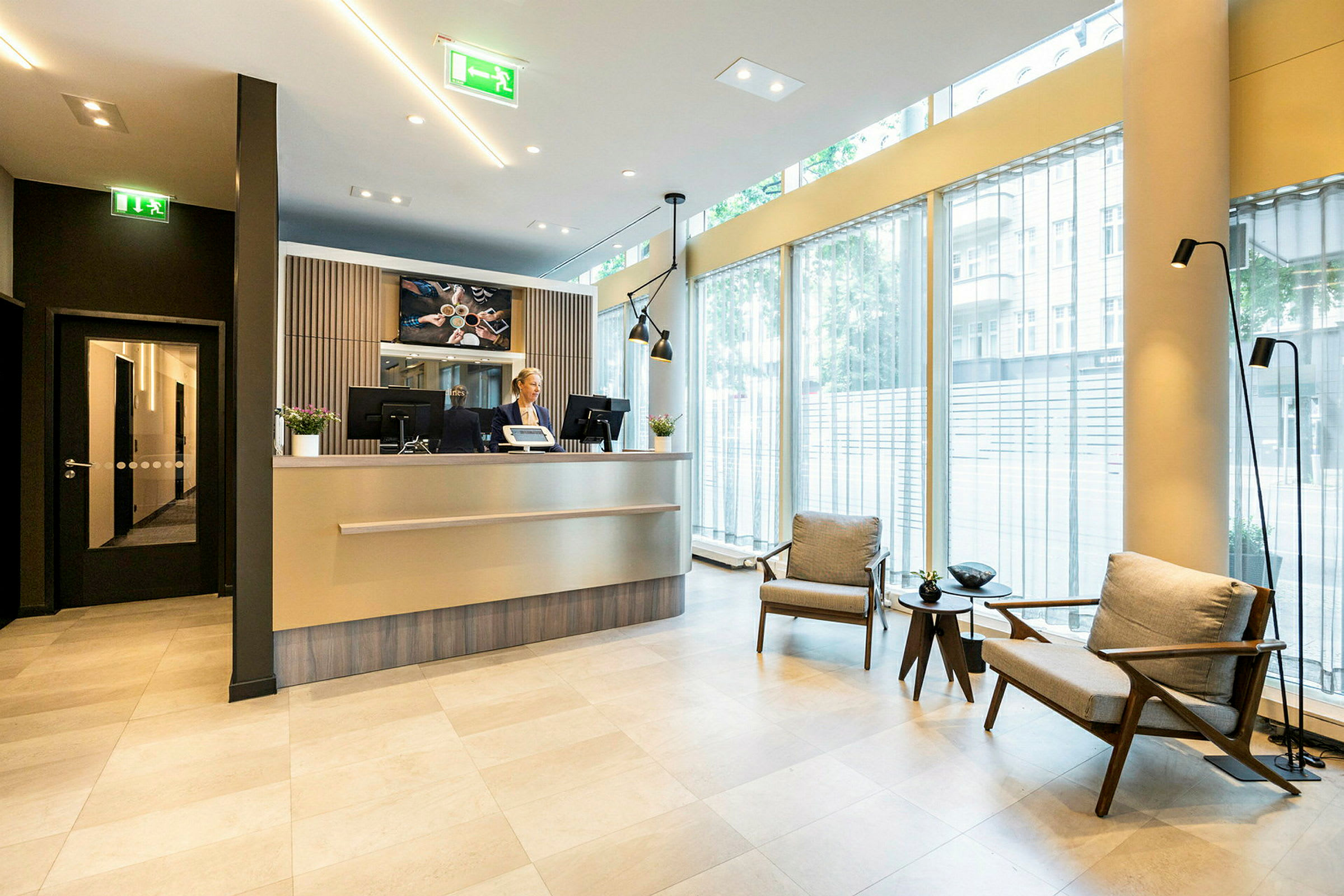 Hotellobby med reception och sittområde, stora fönster. (AI-genererad text)
