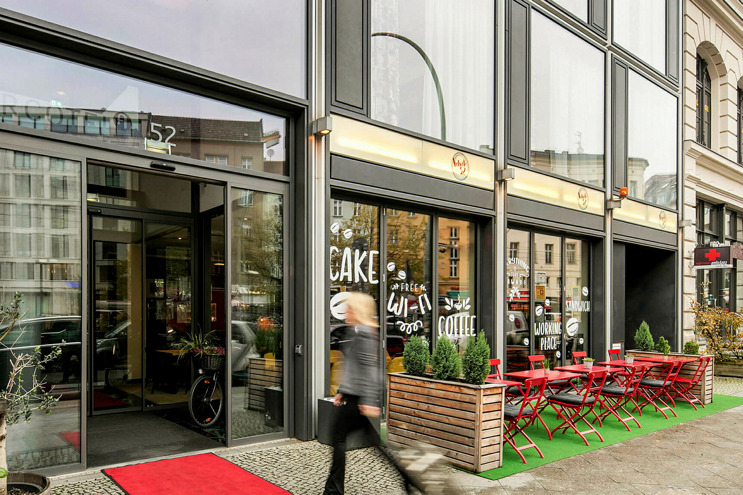 Entrén till en cafébyggnad med uteservering och skyltar i fönstret. (AI-genererad text)