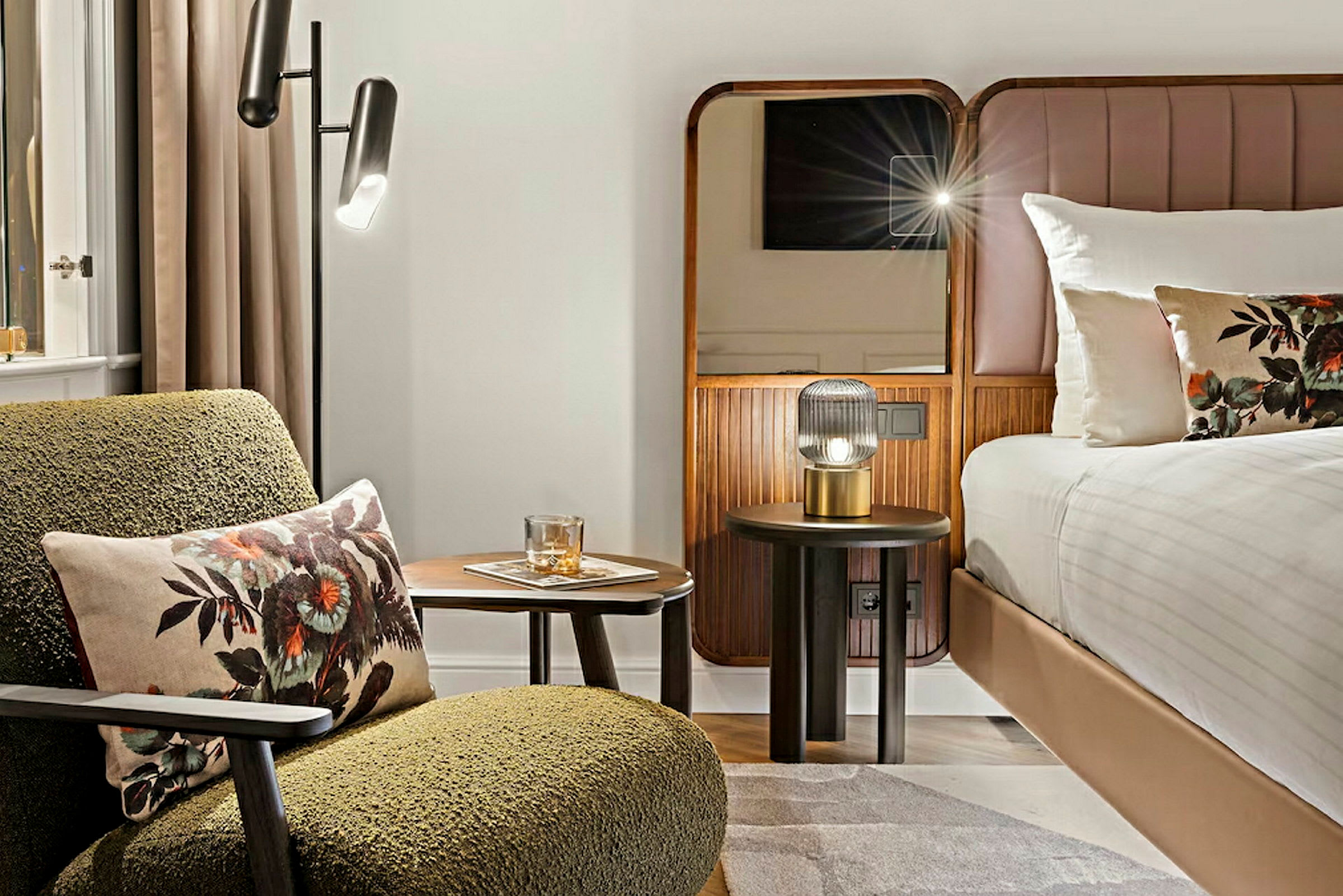 Ett hotellrum med ett modernt och stilrent inrett sovområde, inklusive säng, fåtölj och nattbord. (AI-genererad text)