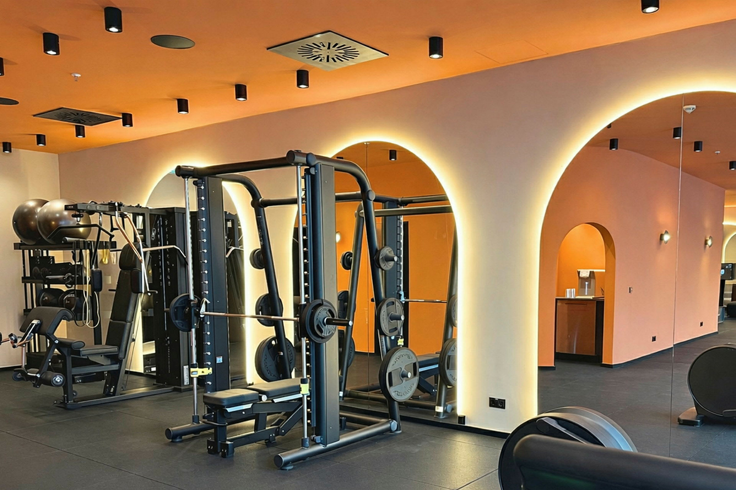 Ett gym med träningsutrustning och orange väggar med ljusbågar. (AI-genererad text)