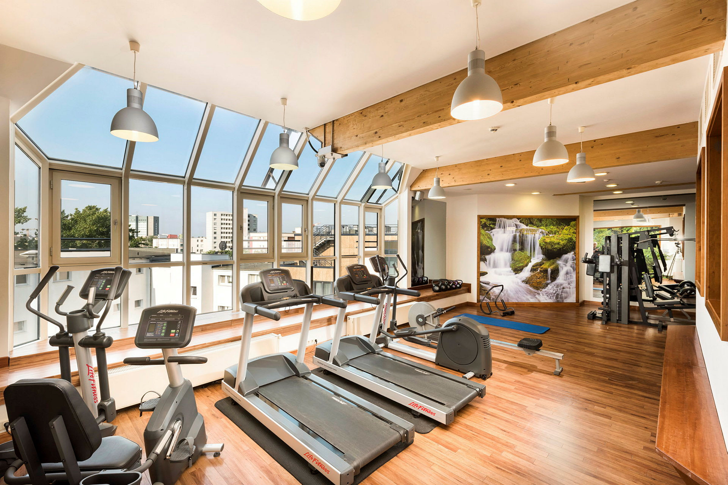 Ett gym med träningsmaskiner, ljus inredning och stora fönster. (AI-genererad text)