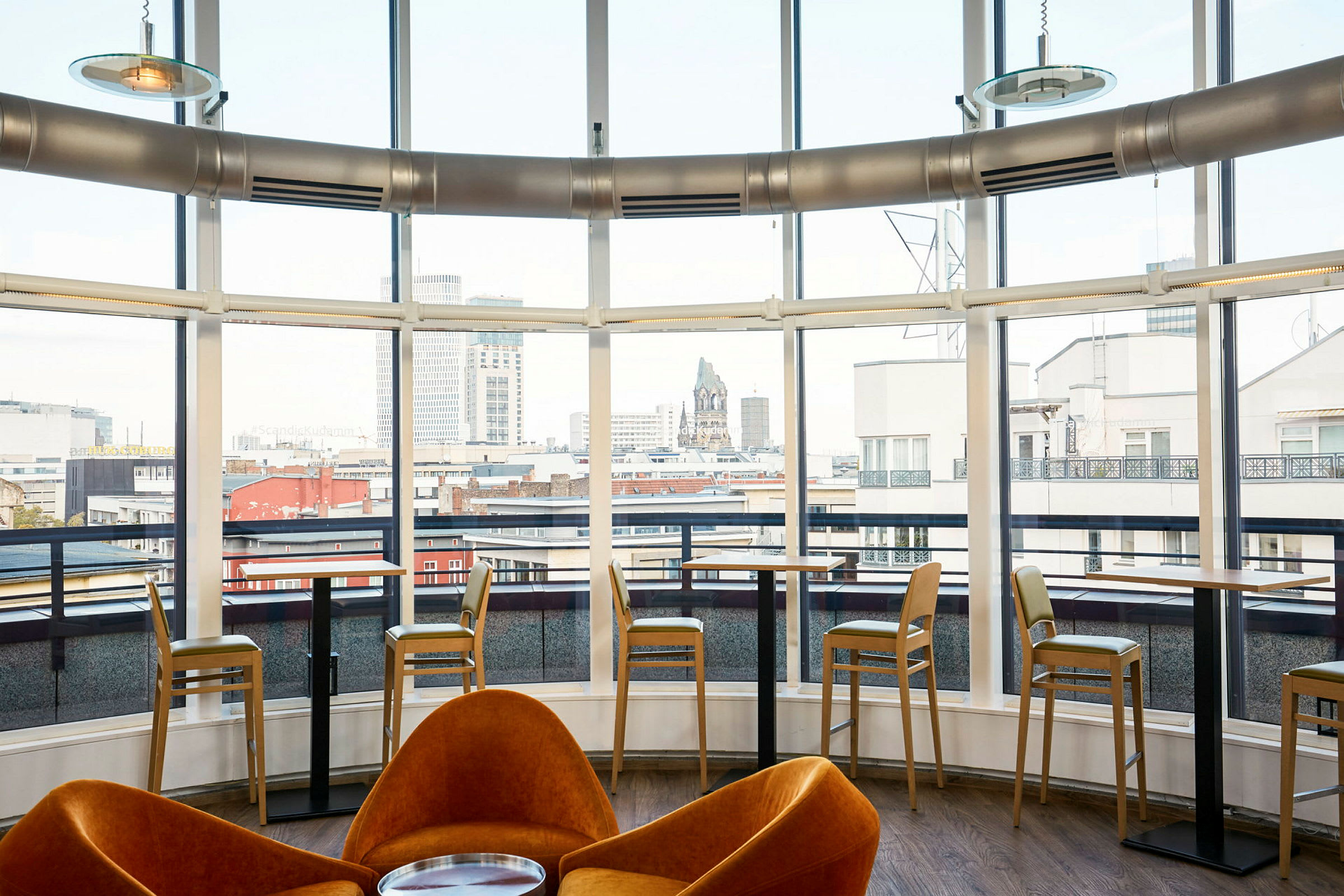 Inomhusvy av ett modernt café med stora fönster mot staden. (AI-genererad text)