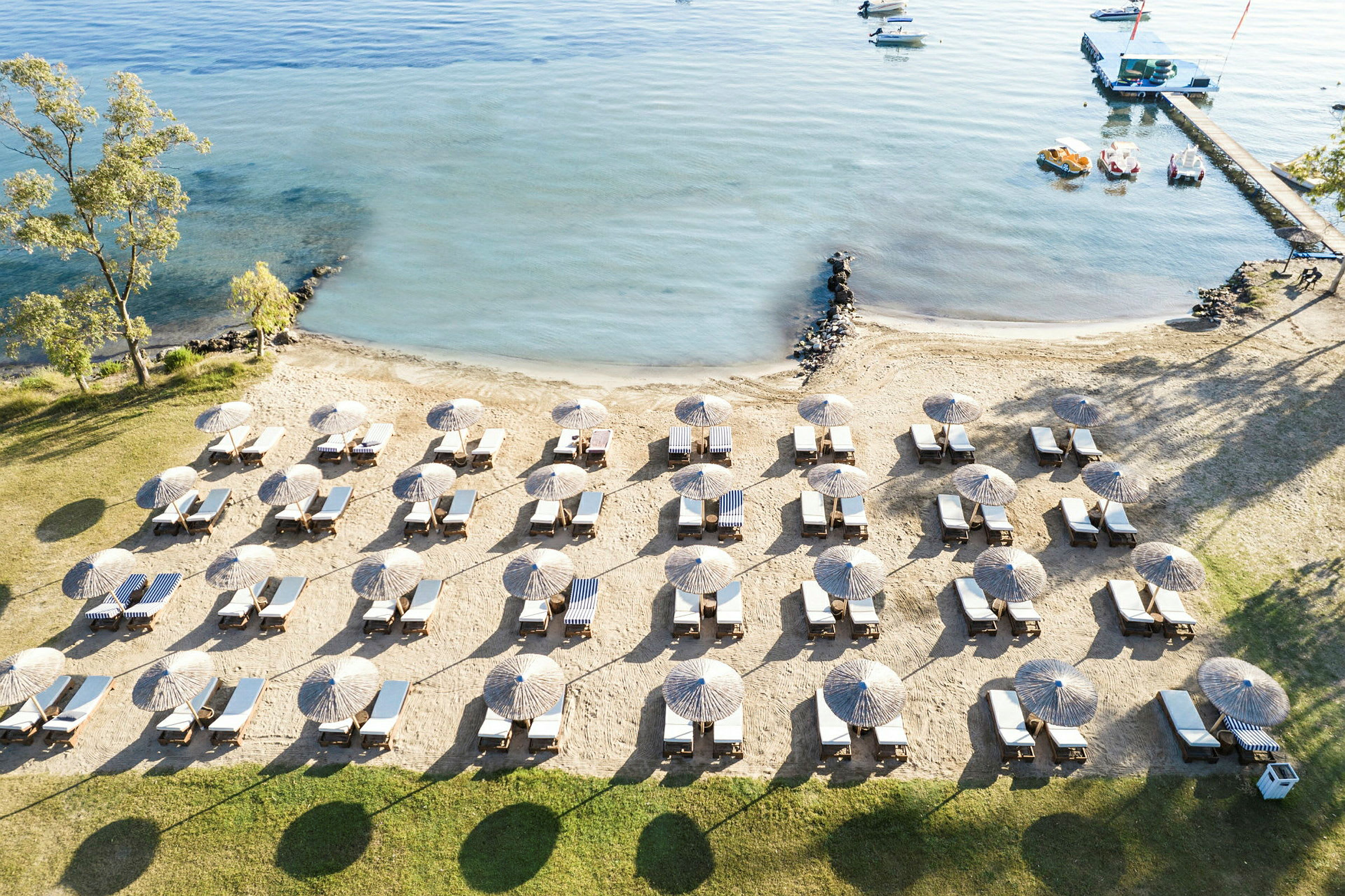 Strand med solstolar och parasoller i rader nära vatten. (AI-genererad text)