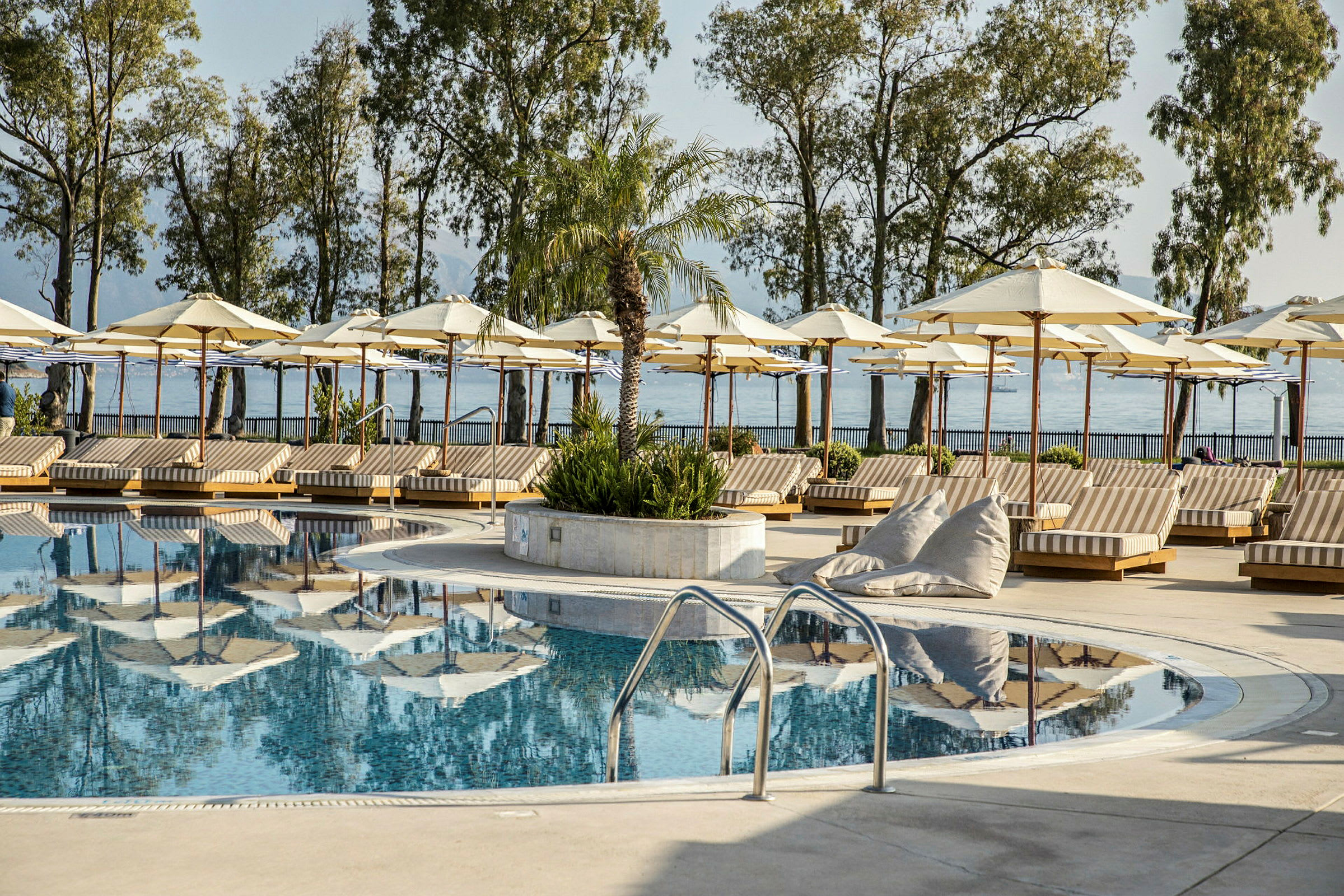 Solstolar med parasoller runt en pool nära stranden. (AI-genererad text)