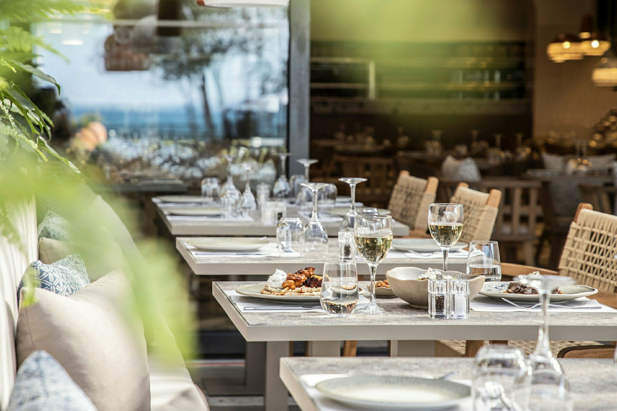 Bild av dukade bord på en restaurang med tallrikar, glas och stolar. (AI-genererad text)