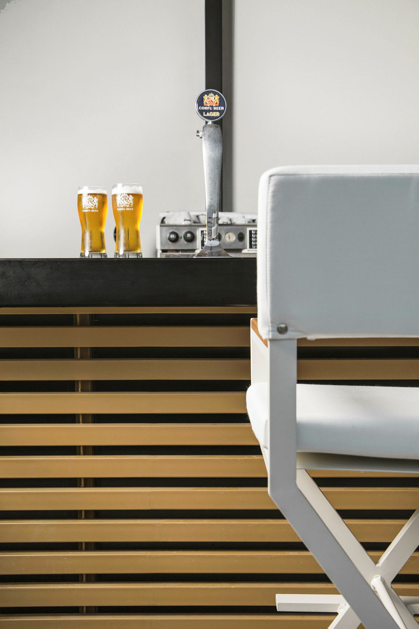 En bar med en ölkran och två glas fyllda med öl. En vit stol syns till höger. (AI-genererad text)