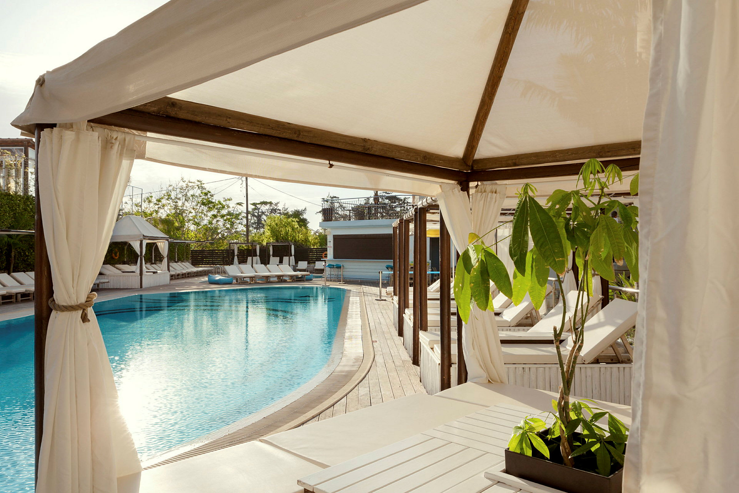 En pool med solstolar och tältliknande konstruktioner omkring. (AI-genererad text)