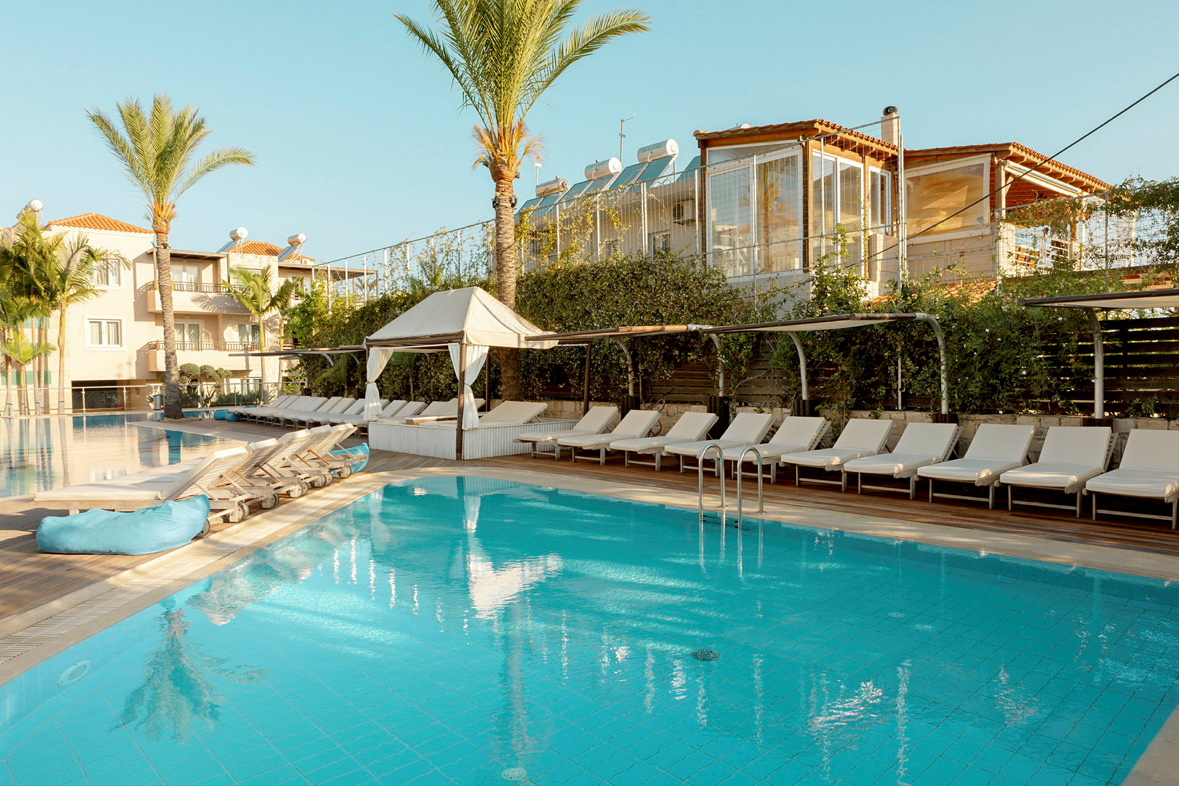 Bild av en pool omgiven av solstolar, med ett hotell i bakgrunden. (AI-genererad text)