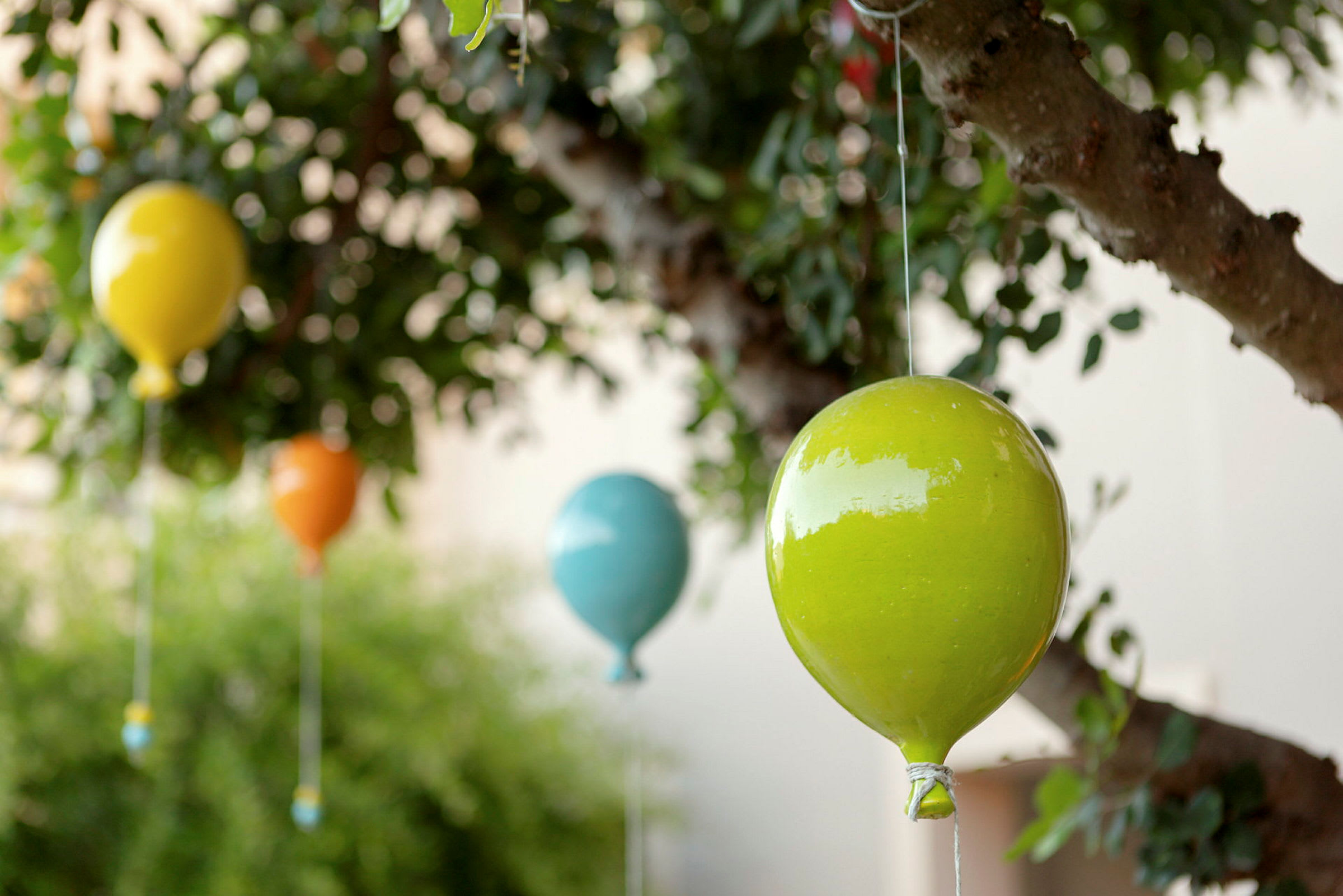 Färgglada dekorationer i form av luftballonger hänger i ett träd. (AI-genererad text)