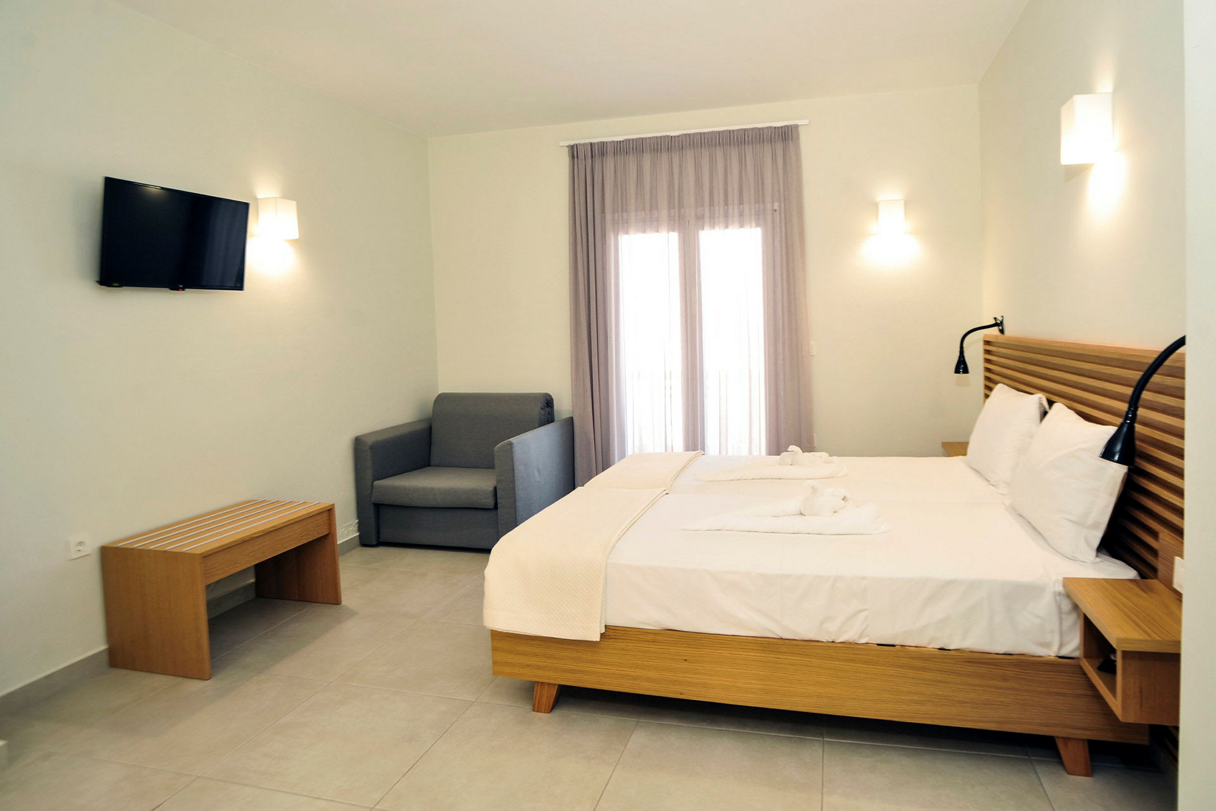 Hotellrum med dubbelsäng, tv på väggen och en soffa. (AI-genererad text)