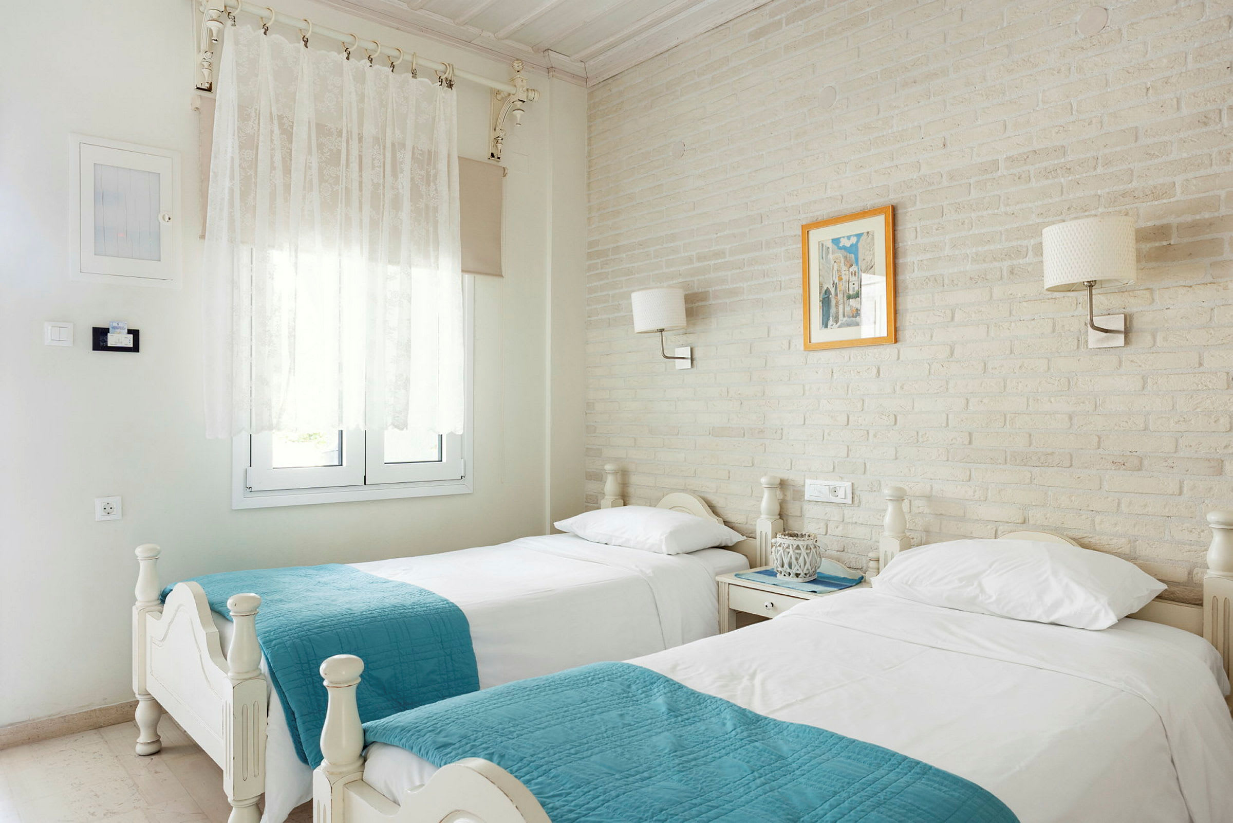 Hotellrum med två enkelsängar, vita täcken och turkosa plädar. (AI-genererad text)