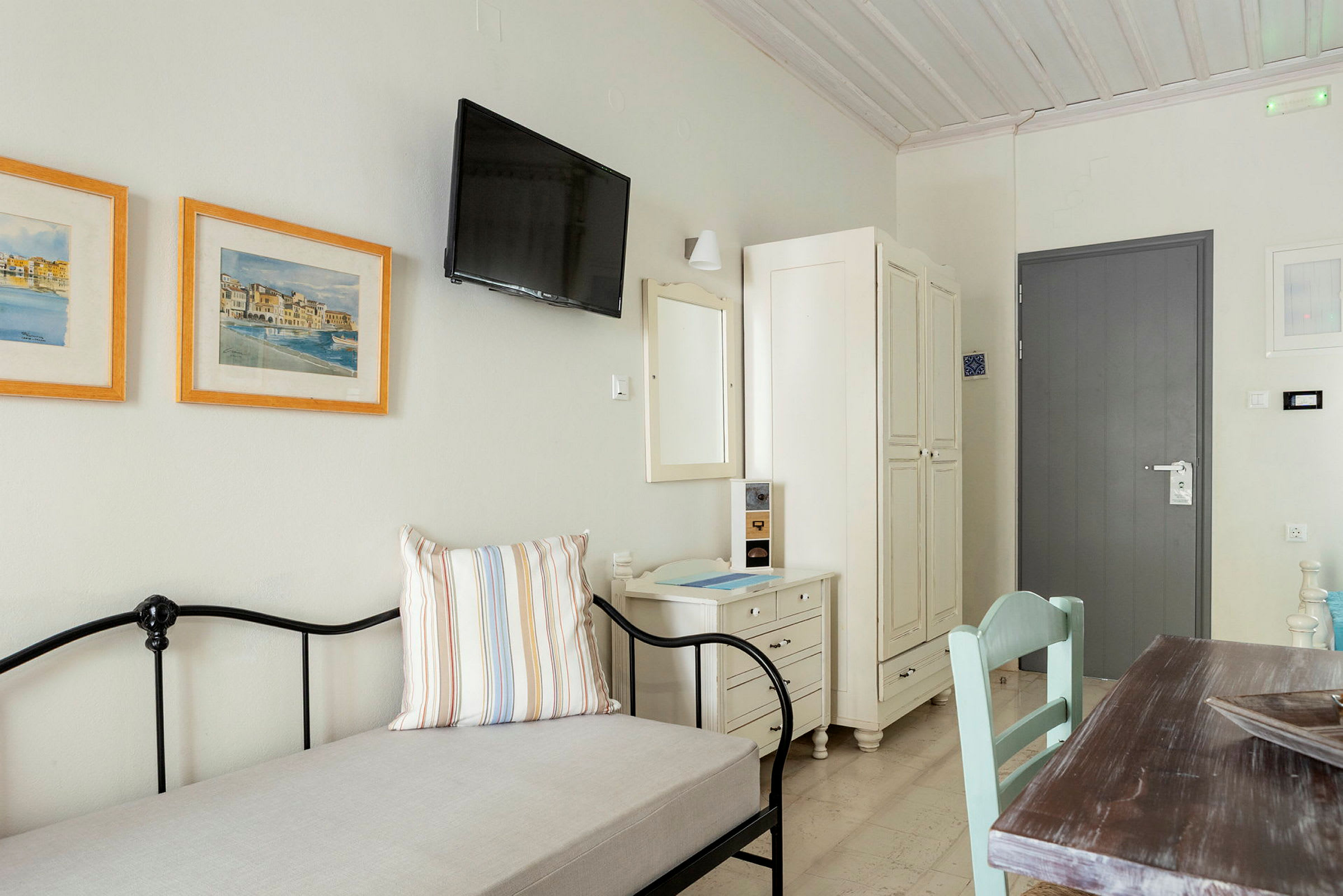 Ett ljust och enkelt möblerat hotellrum med en dörr, garderob, tavlor och bord. (AI-genererad text)