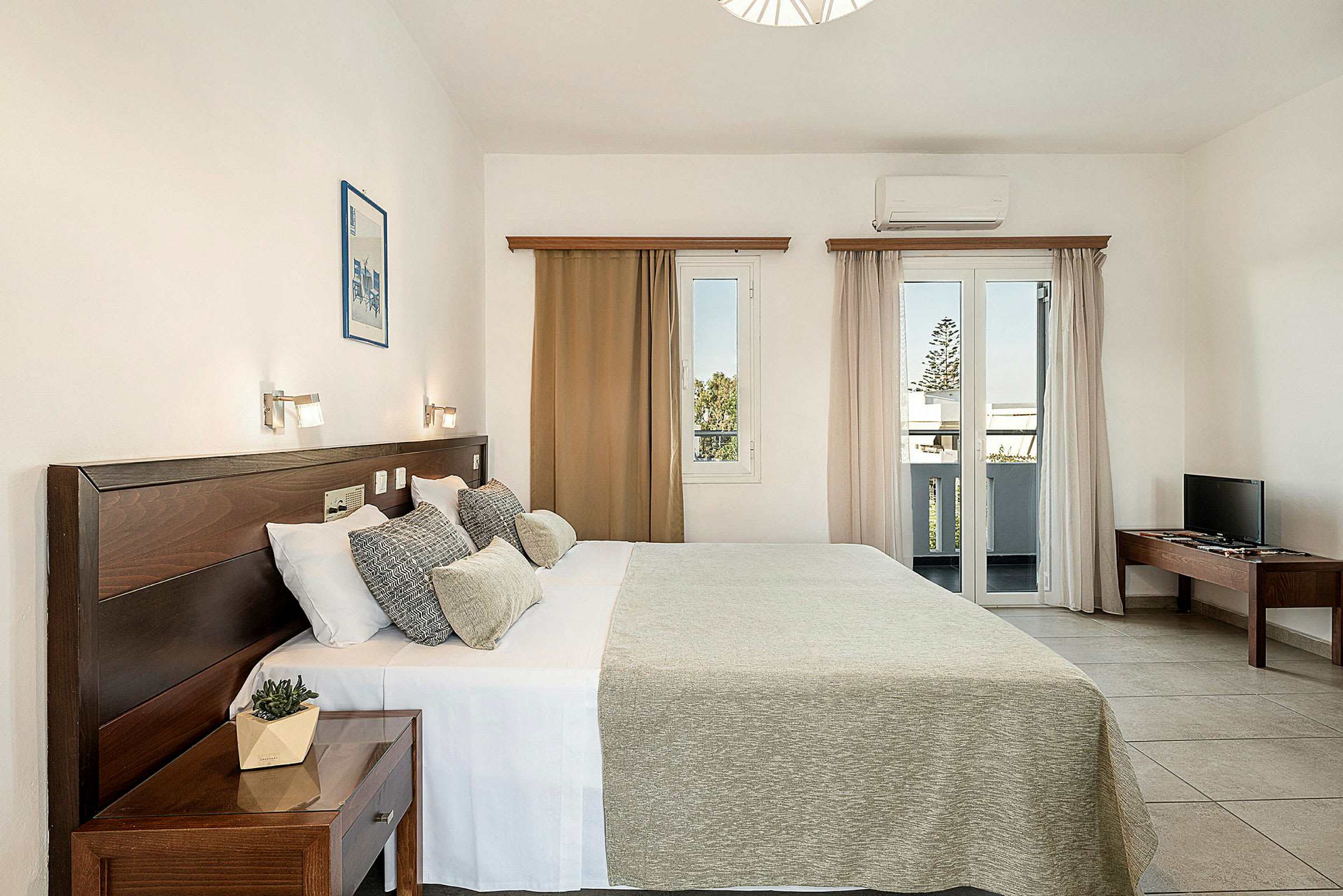 Ett hotellrum med dubbelsäng, sängbord, fönster med utsikt, och TV på ett bord. (AI-genererad text)