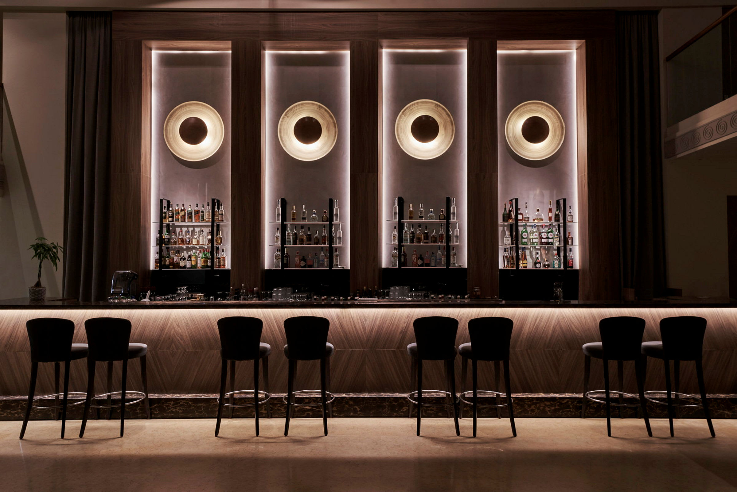 Elegant hotellbar med höga stolar och flaskor uppställda bakom counteren. (AI-genererad text)