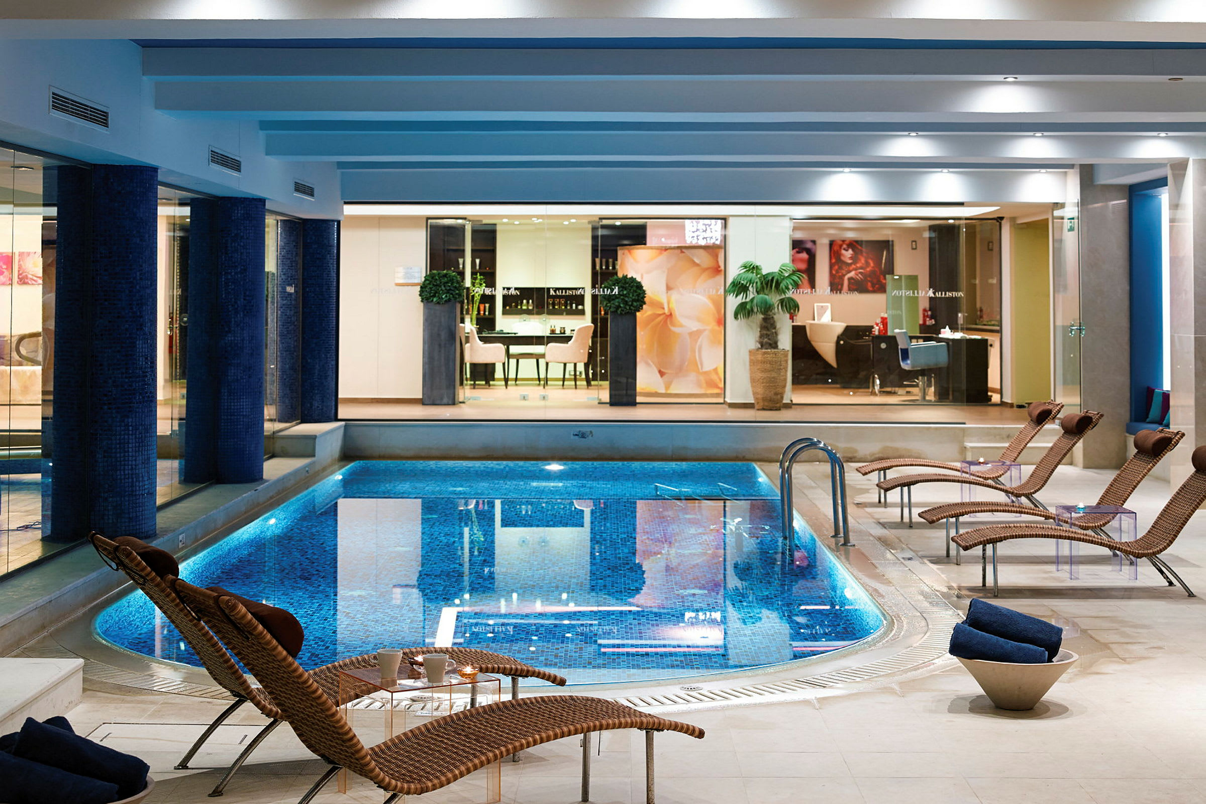En inomhuspool i ett elegant spa med solstolar runtom. (AI-genererad text)
