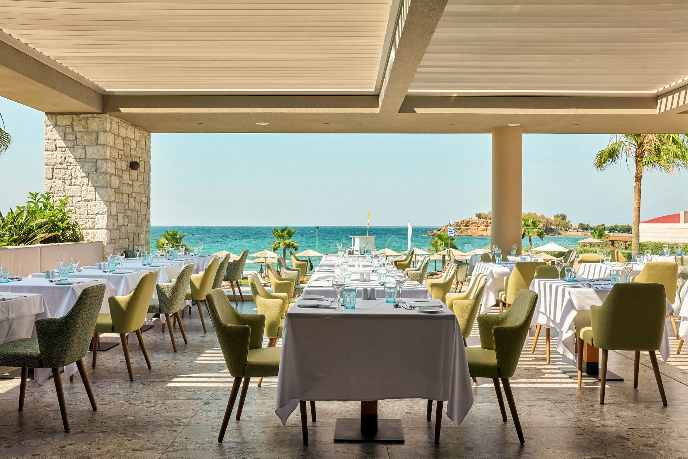 Restaurang med dukade bord och utsikt mot havet. (AI-genererad text)