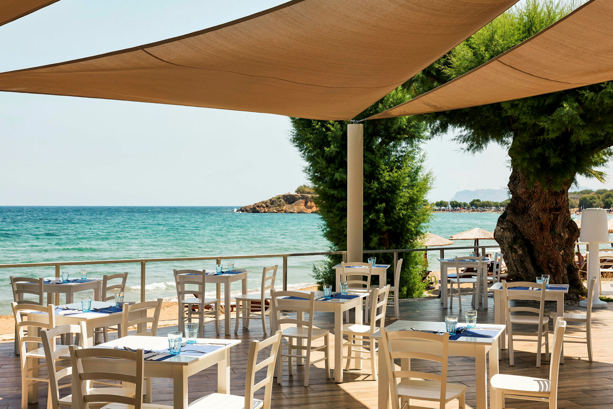 Restaurang med vita bord och stolar vid havet. (AI-genererad text)