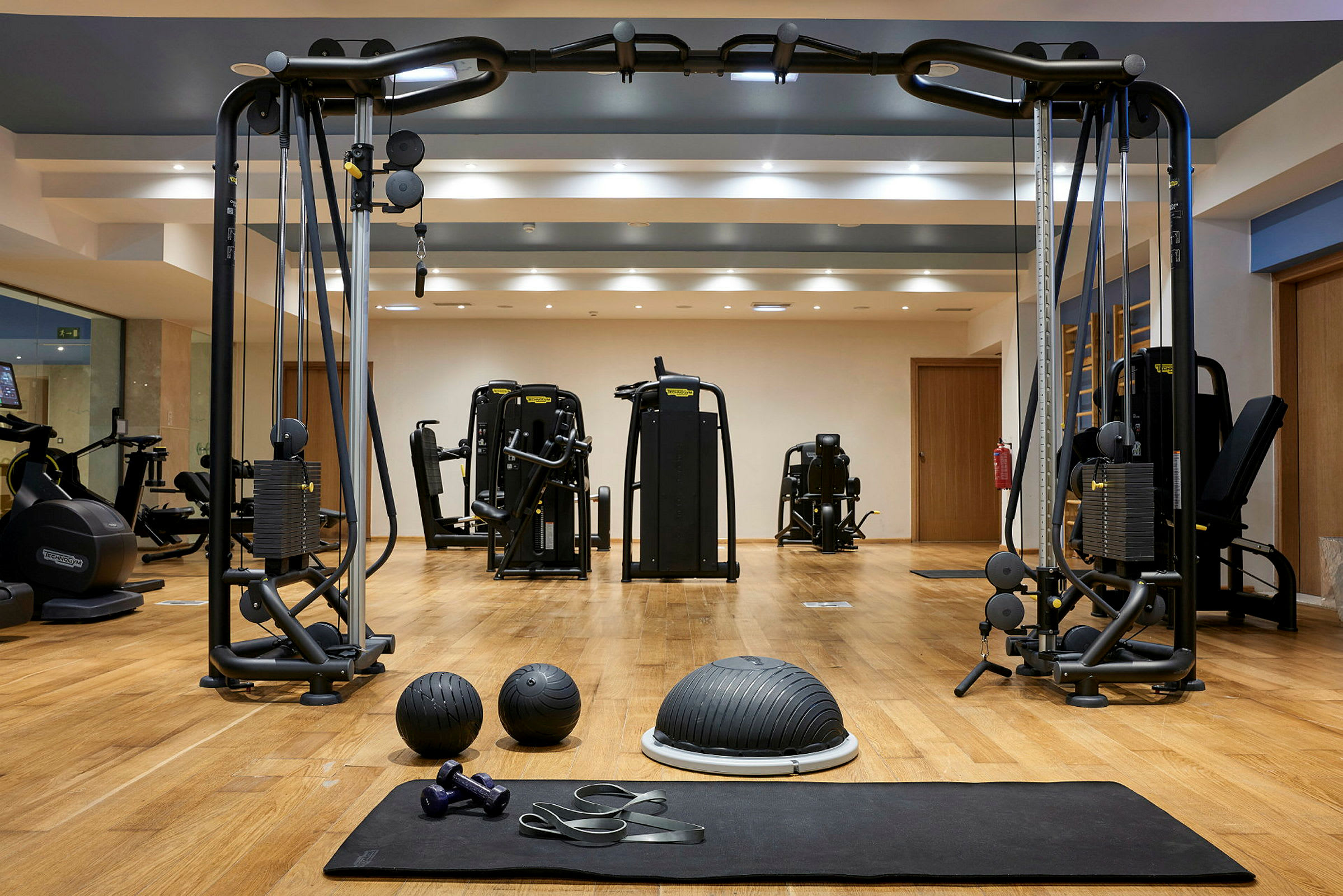 Ett gym med träningsmaskiner, träningsbollar, hantlar och motståndsband. (AI-genererad text)