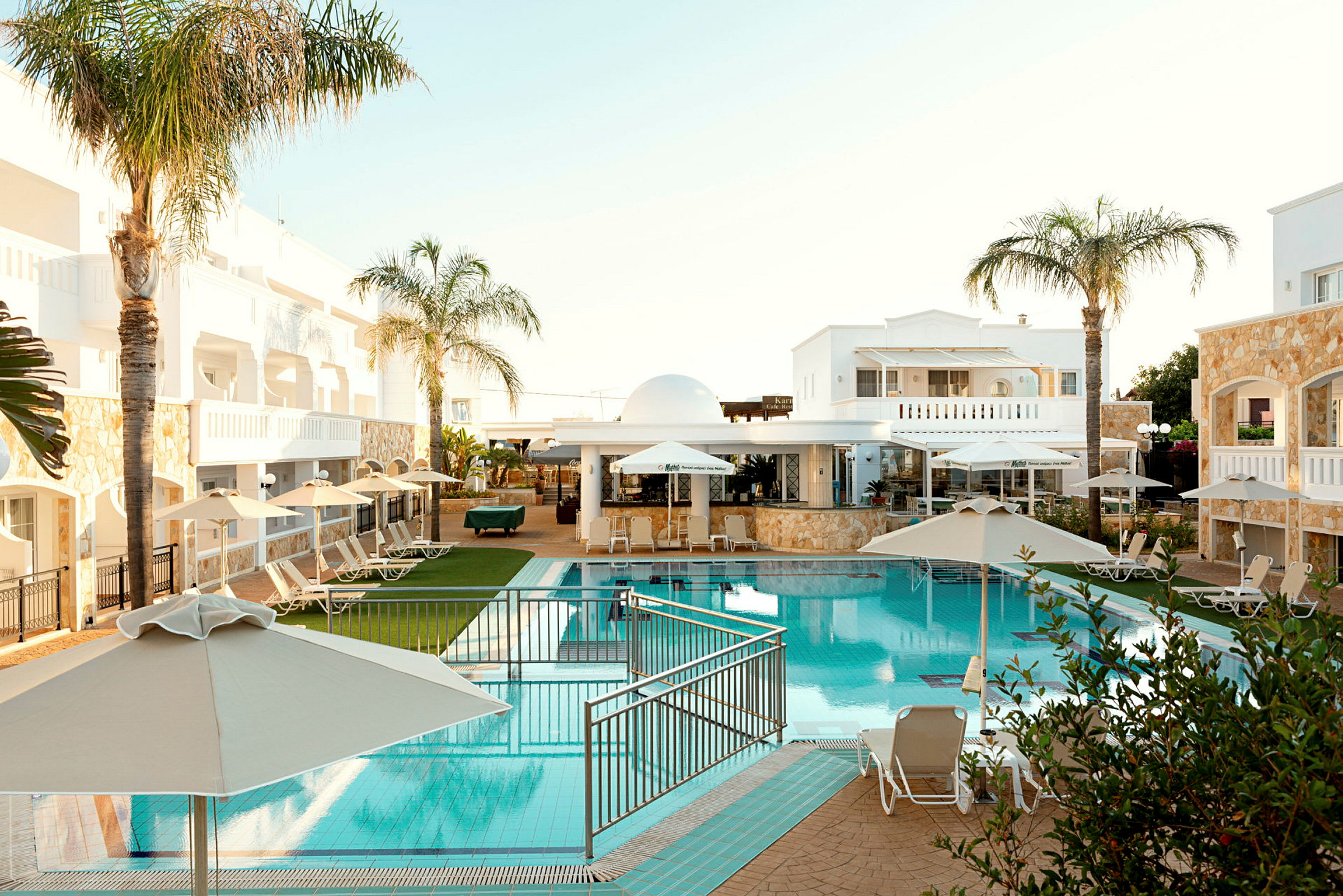 Hotellområde med pool, solstolar och parasoller. (AI-genererad text)