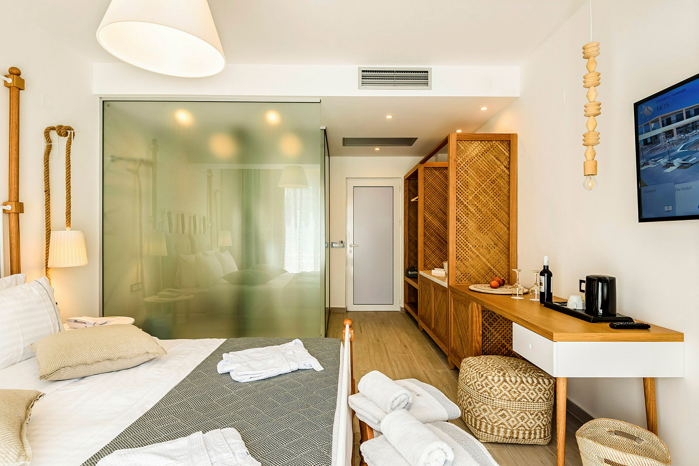 Ett hotellrum med en dubbelsäng, trädetaljer och glasvägg som delar av rummet. (AI-genererad text)