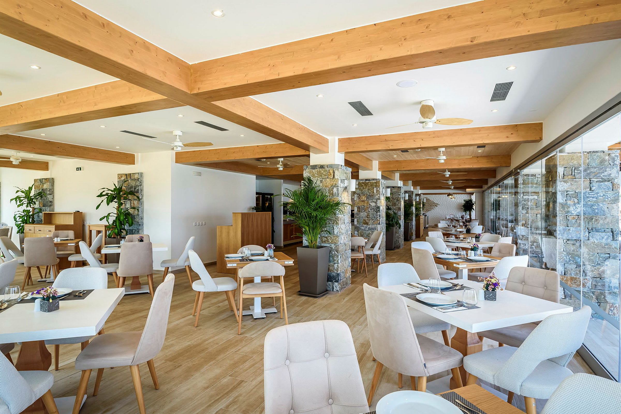 En restauranglokal med stilrena möbler, bord , stolar samt växter . (AI-genererad text)
