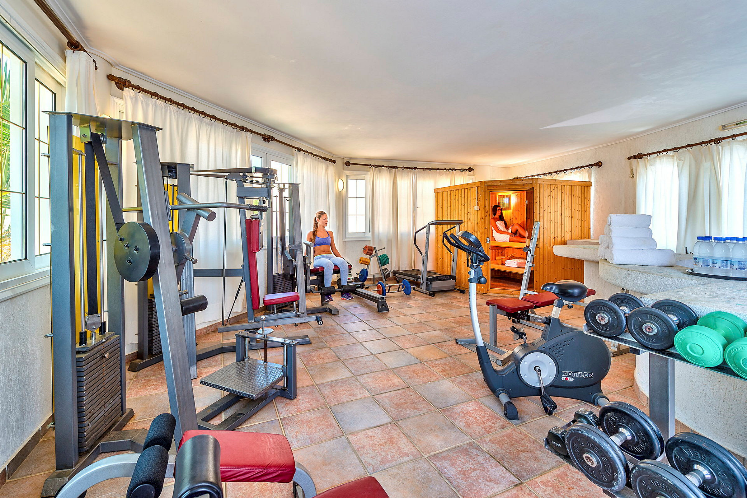 Gym med träningsmaskiner, vikter och en bastu. (AI-genererad text)