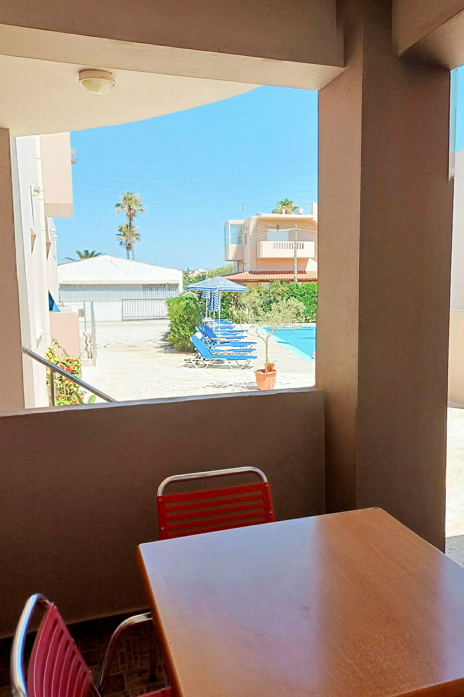 En bord och en stol på en terrass med utsikt över en uteplats och en pool. (AI-genererad text)