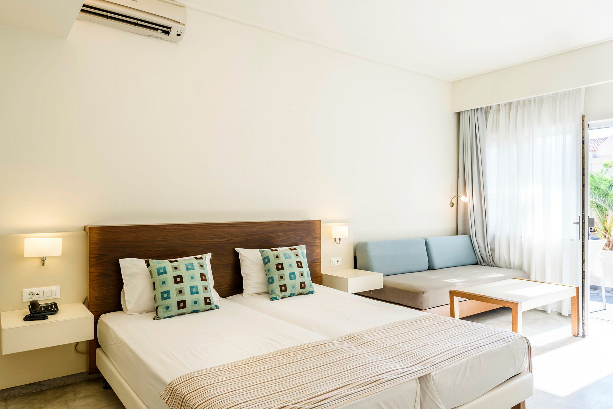 Hotelrum med dubbelsäng, soffa och bord. (AI-genererad text)