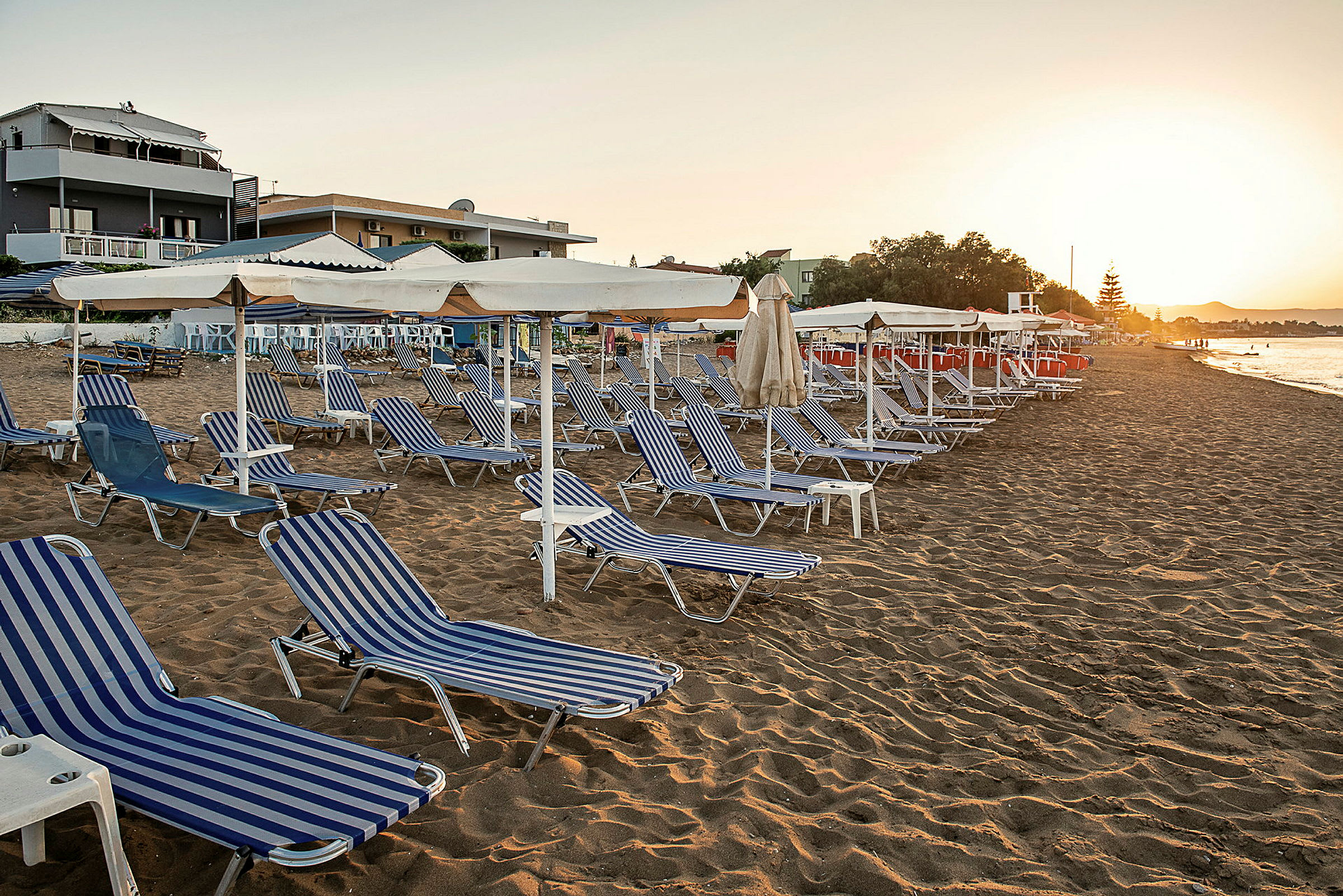 Strand med solstolar och parasoller vid solnedgång. (AI-genererad text)