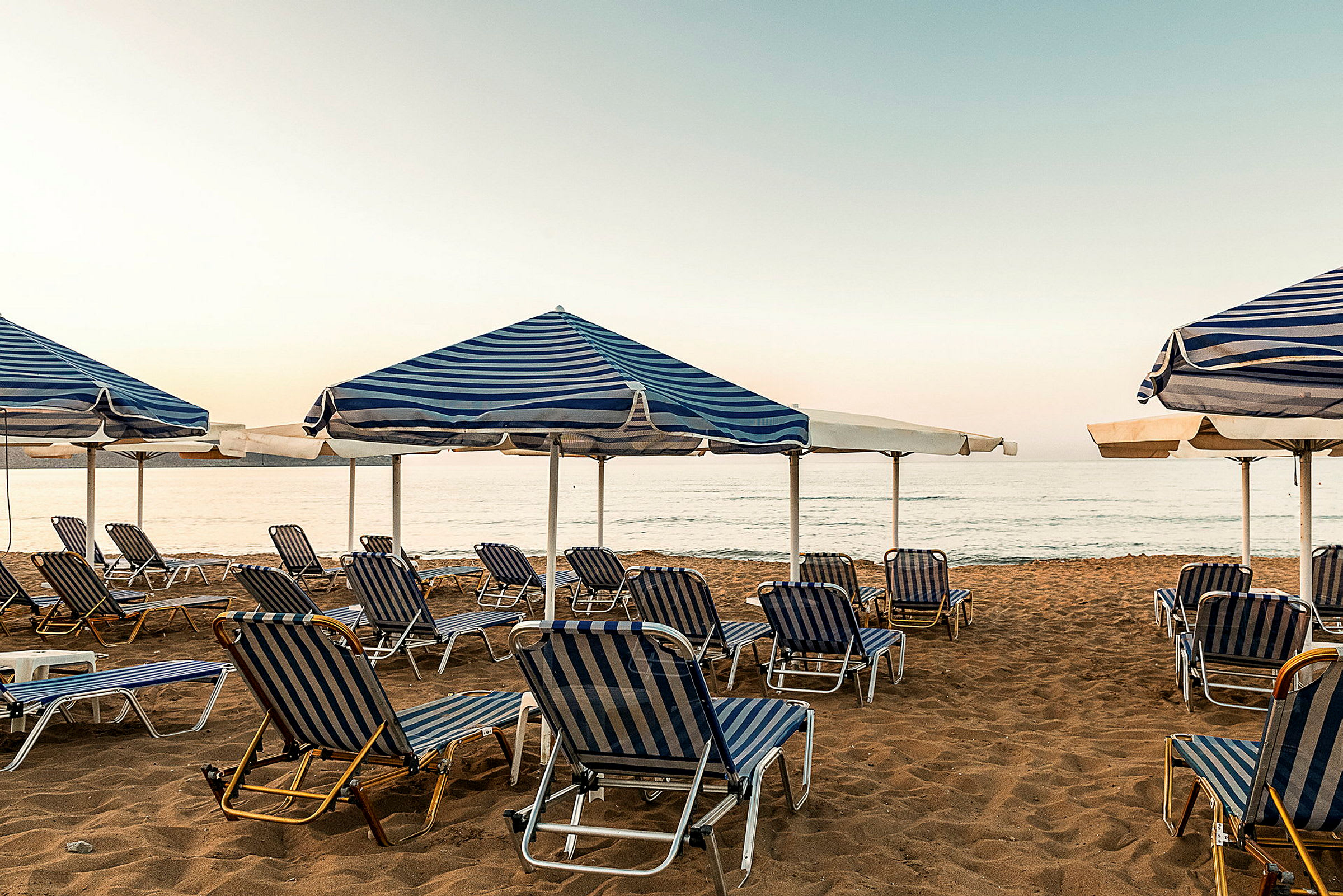 Solstolar och parasoller på en sandstrand vid havet. (AI-genererad text)